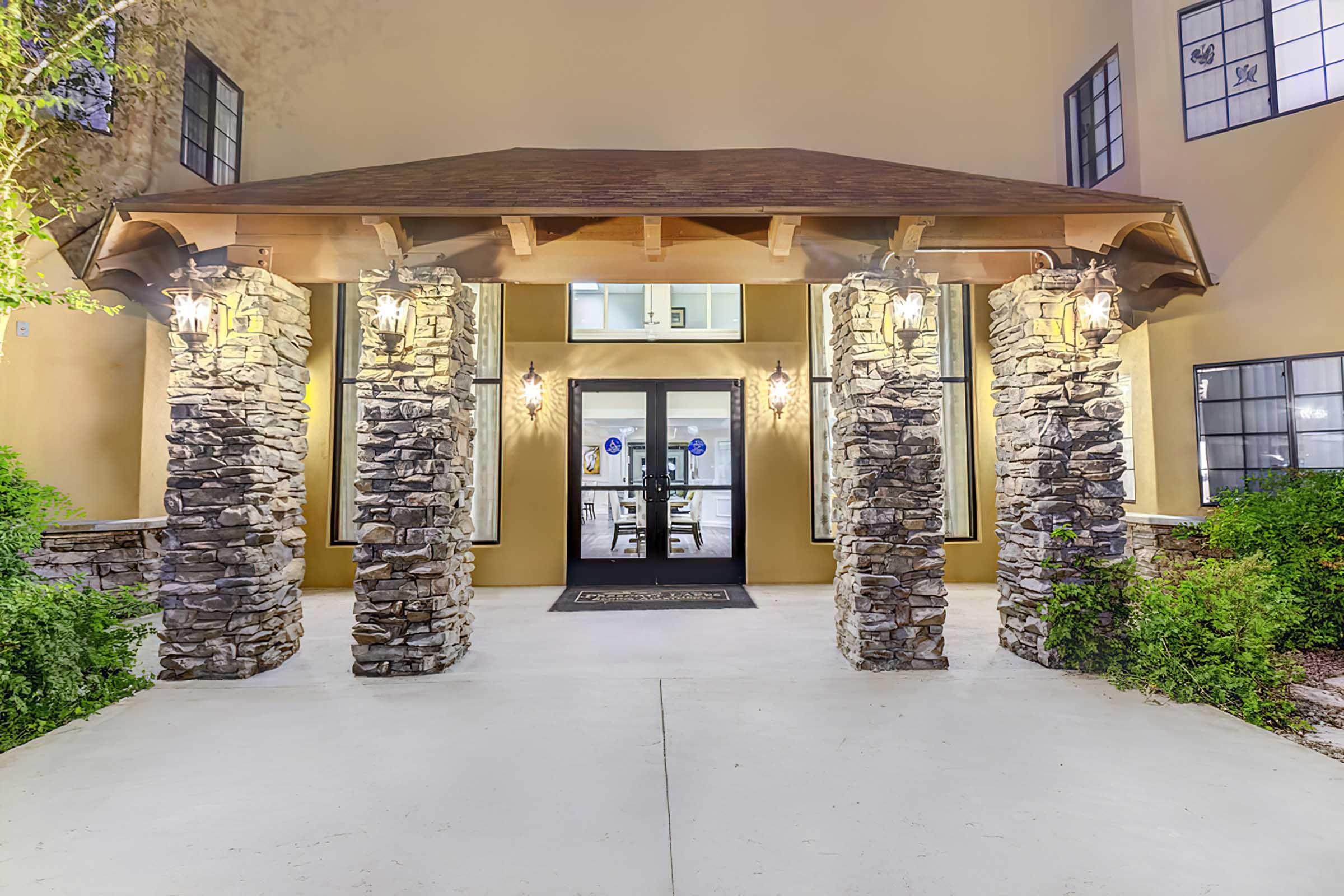 Entrance to a building featuring a covered porch supported by stone pillars.