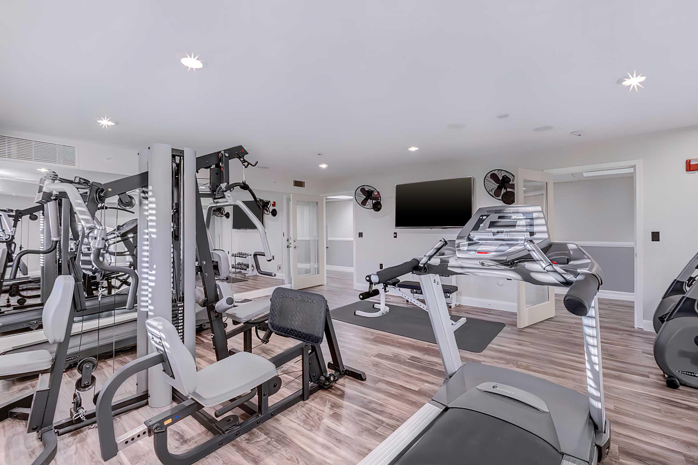  A well-lit fitness gym featuring various exercise equipment, including a treadmill, weight machines, and exercise bikes.