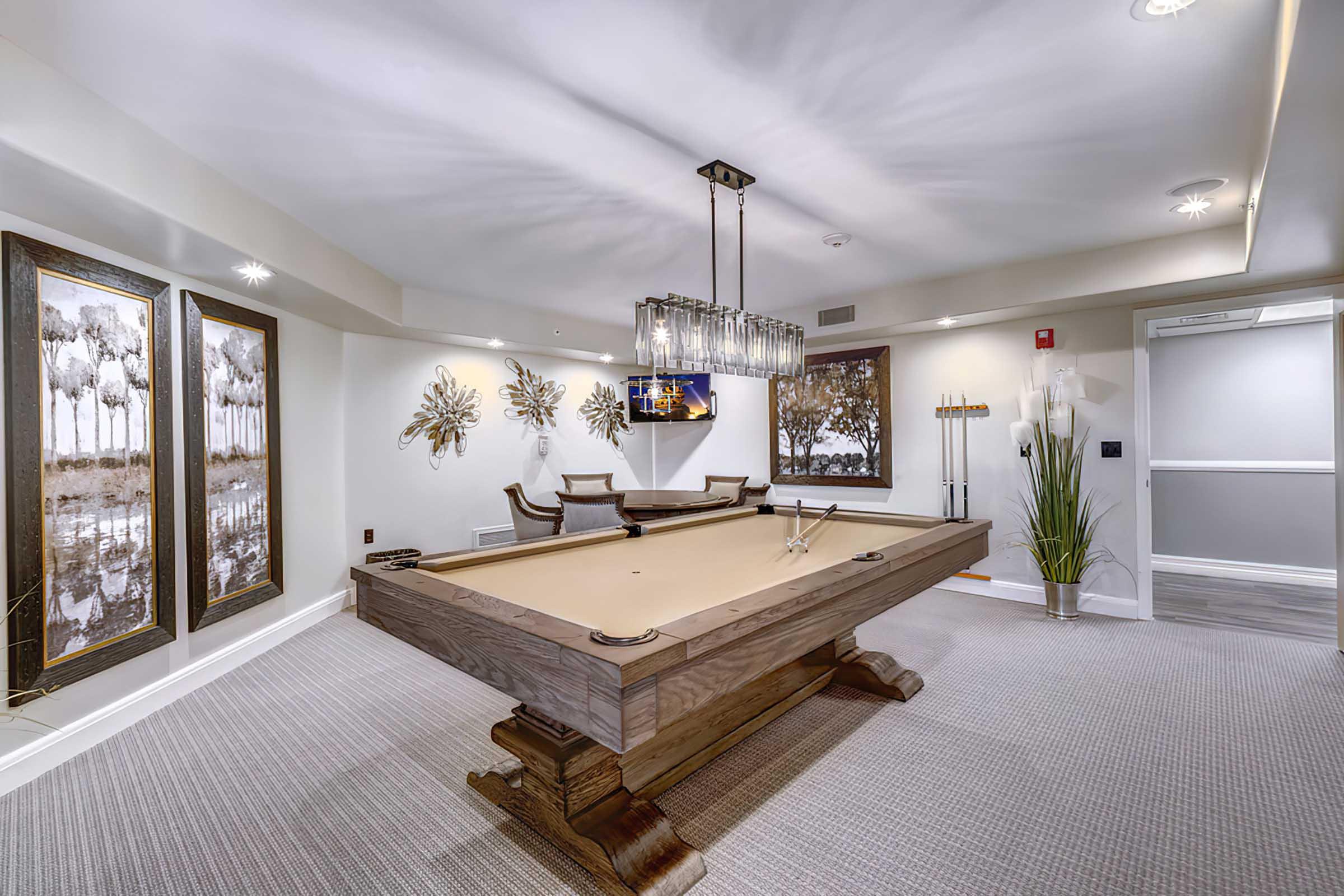 A well-lit recreation room featuring a stylish billiard table in the center. 