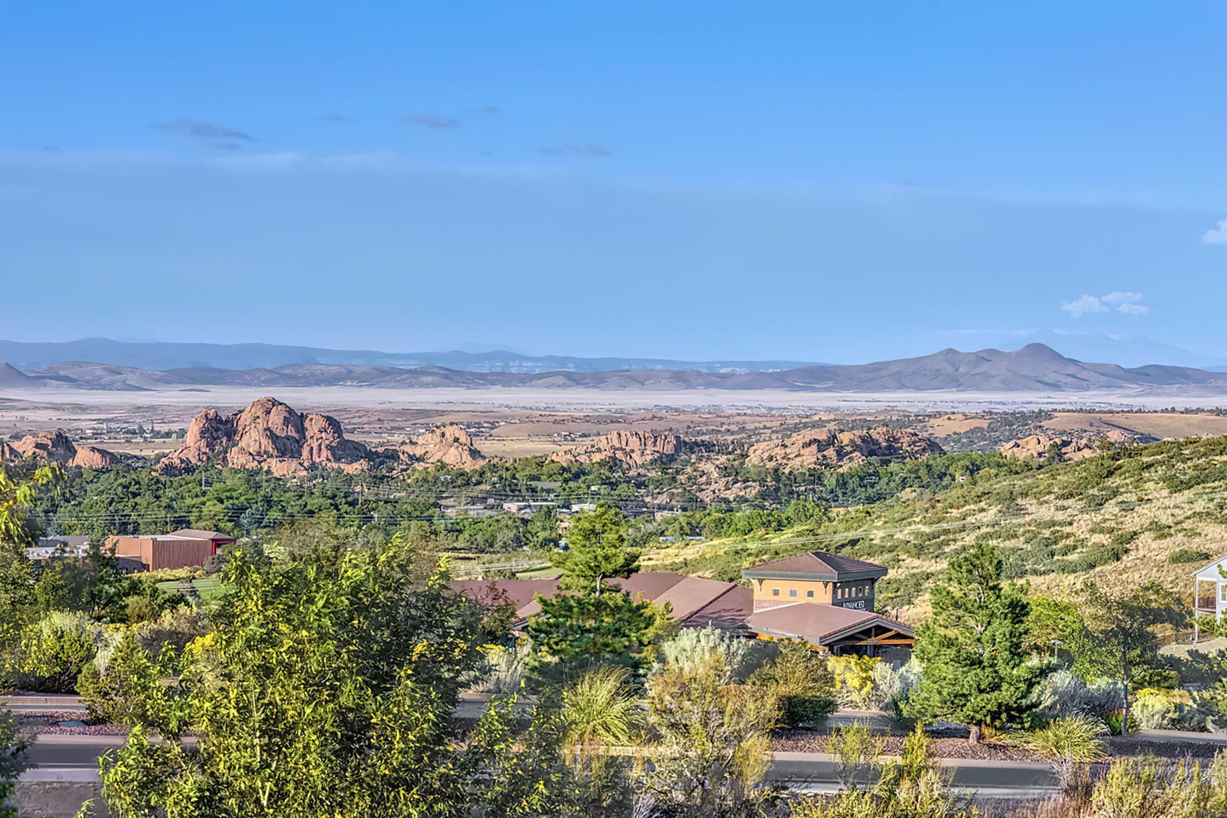 A scenic landscape featuring rocky formations in the foreground, rolling hills, and a vast valley extending into the distance. 