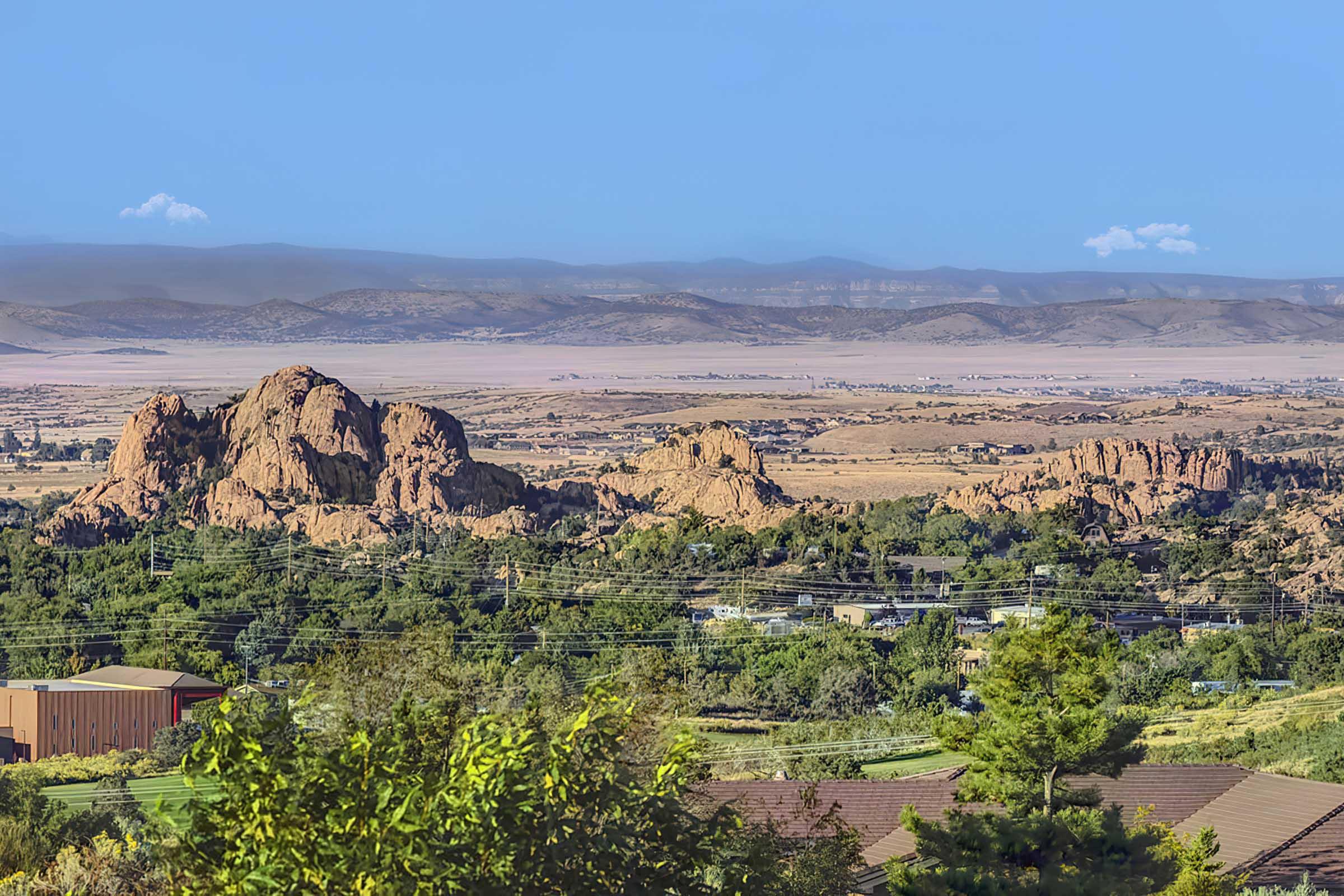  A panoramic view of a rocky landscape with large boulders in the foreground, surrounded by greenery and sparse trees.