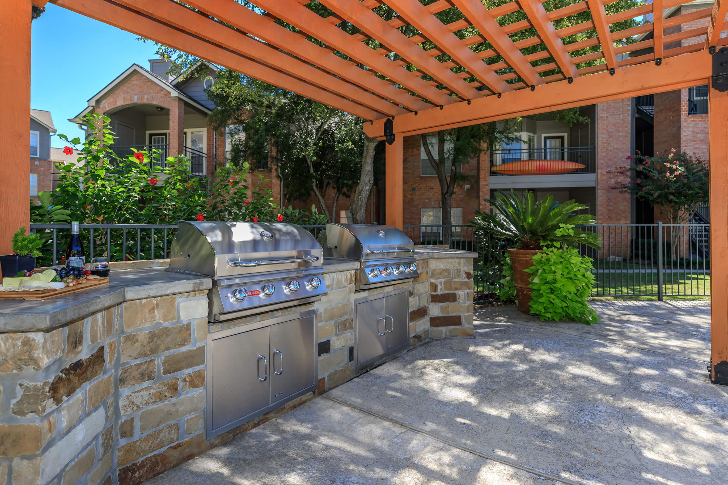 two stainless steel barbecues under a pergola