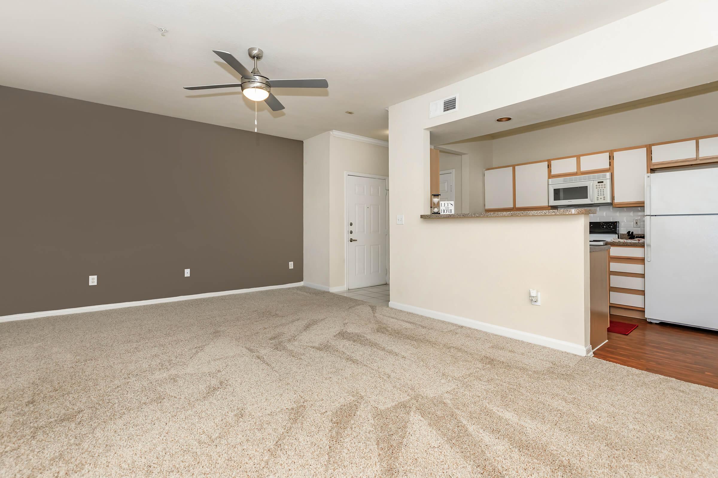a carpeted living room and kitchen with wooden floor