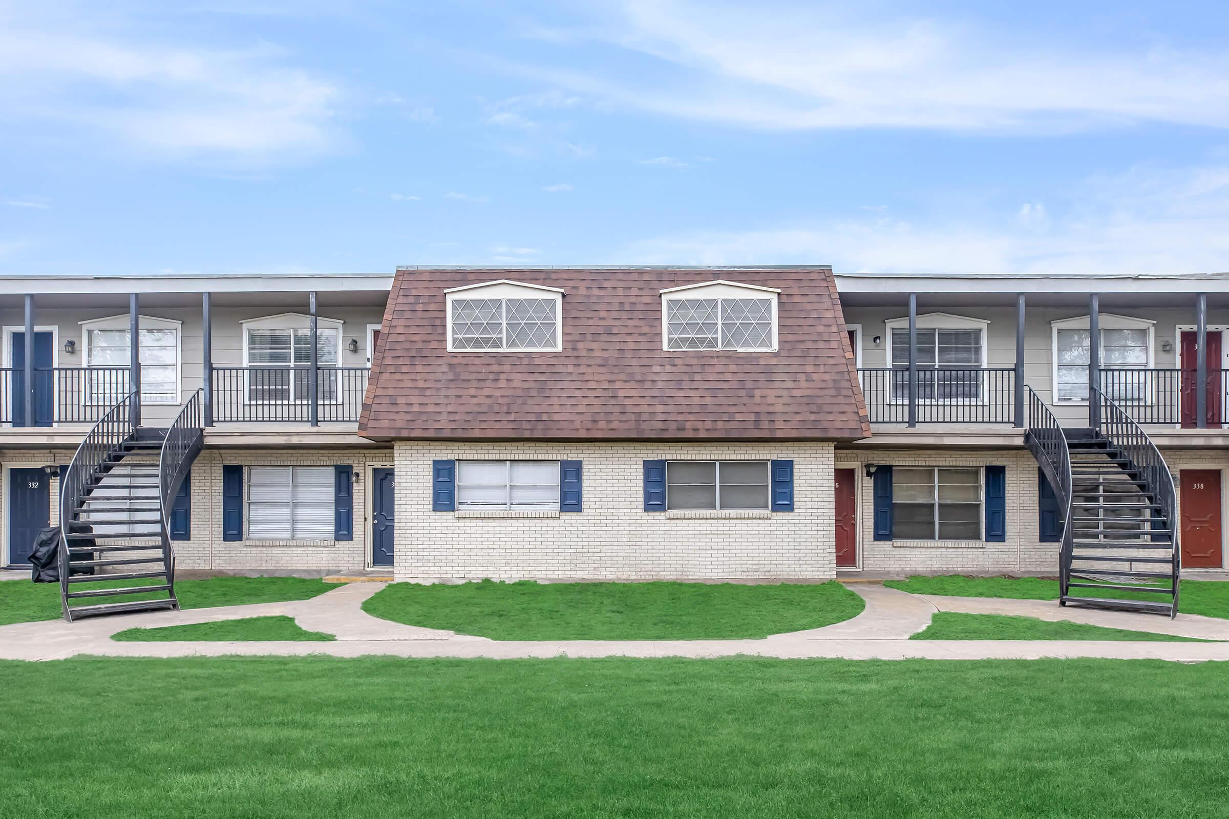 a large brick building with grass in front of a house