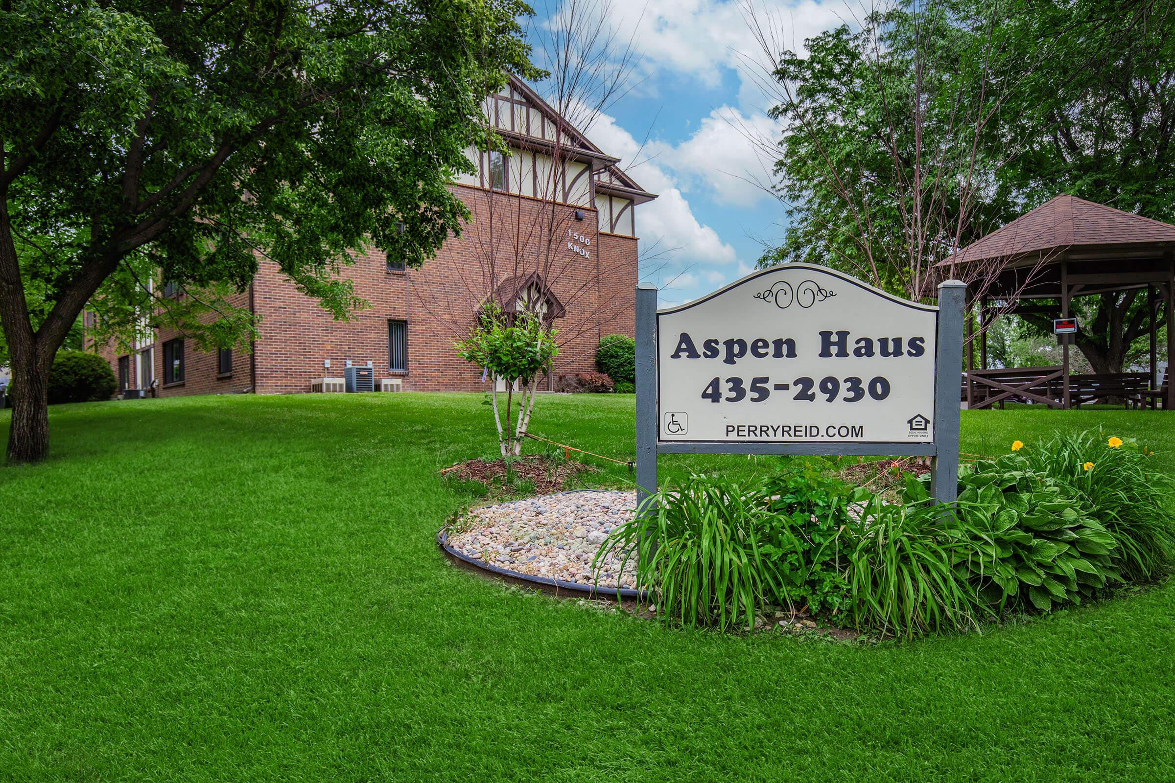 a house that has a sign on a lush green field