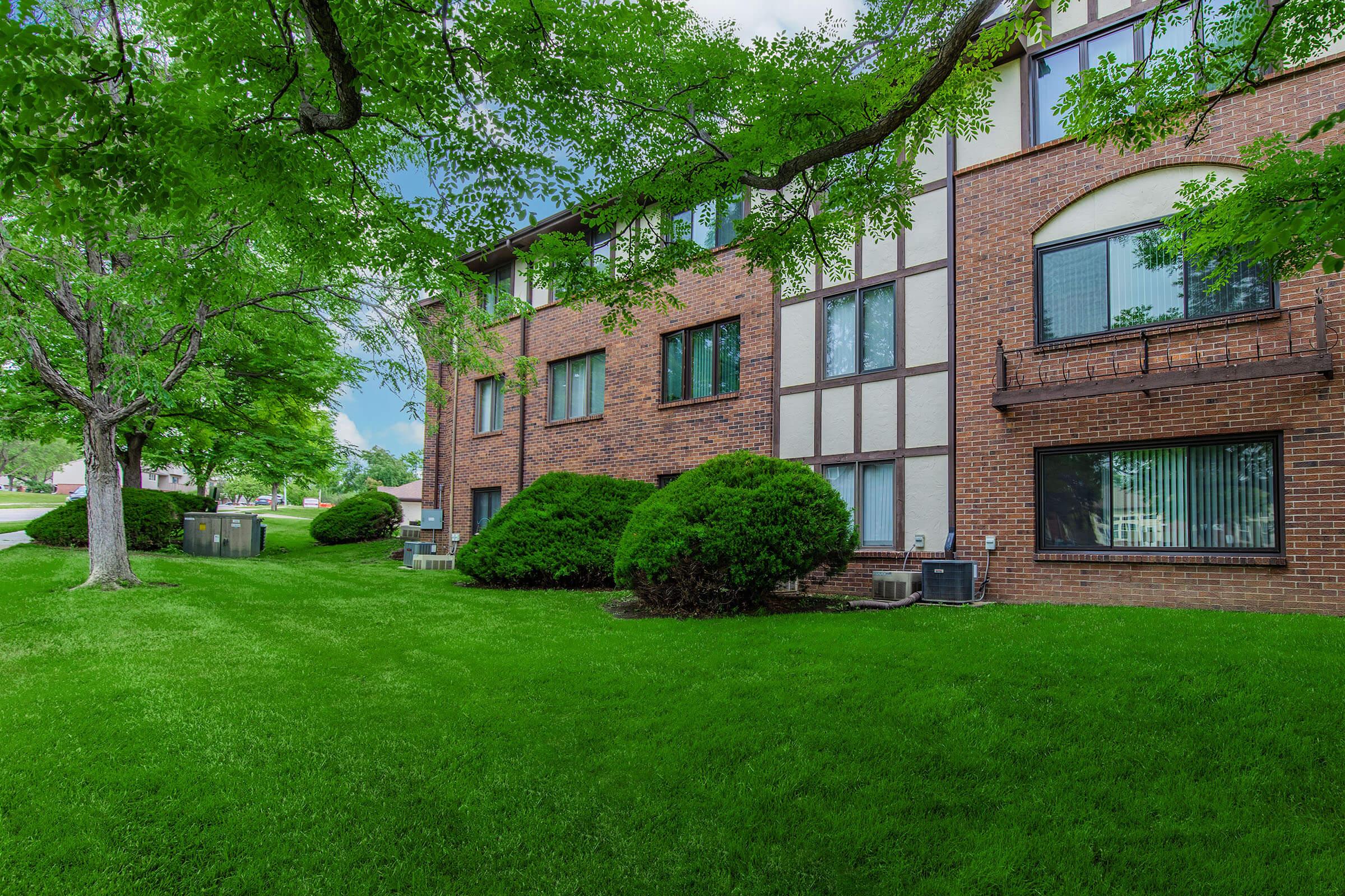 a large brick building with green grass in front of a house