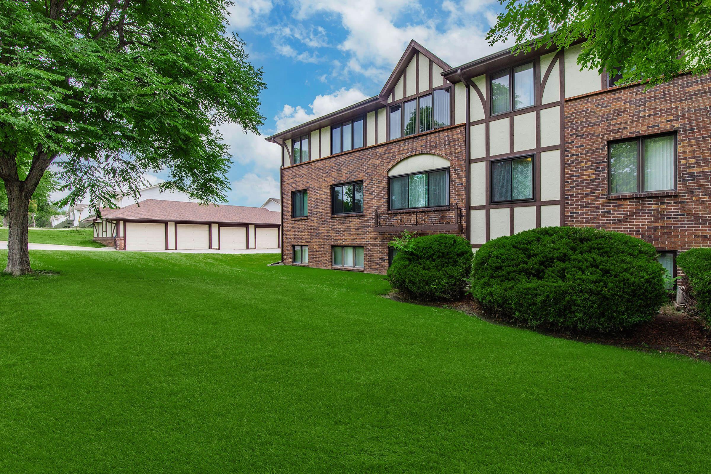 a large brick building with green grass in front of a house