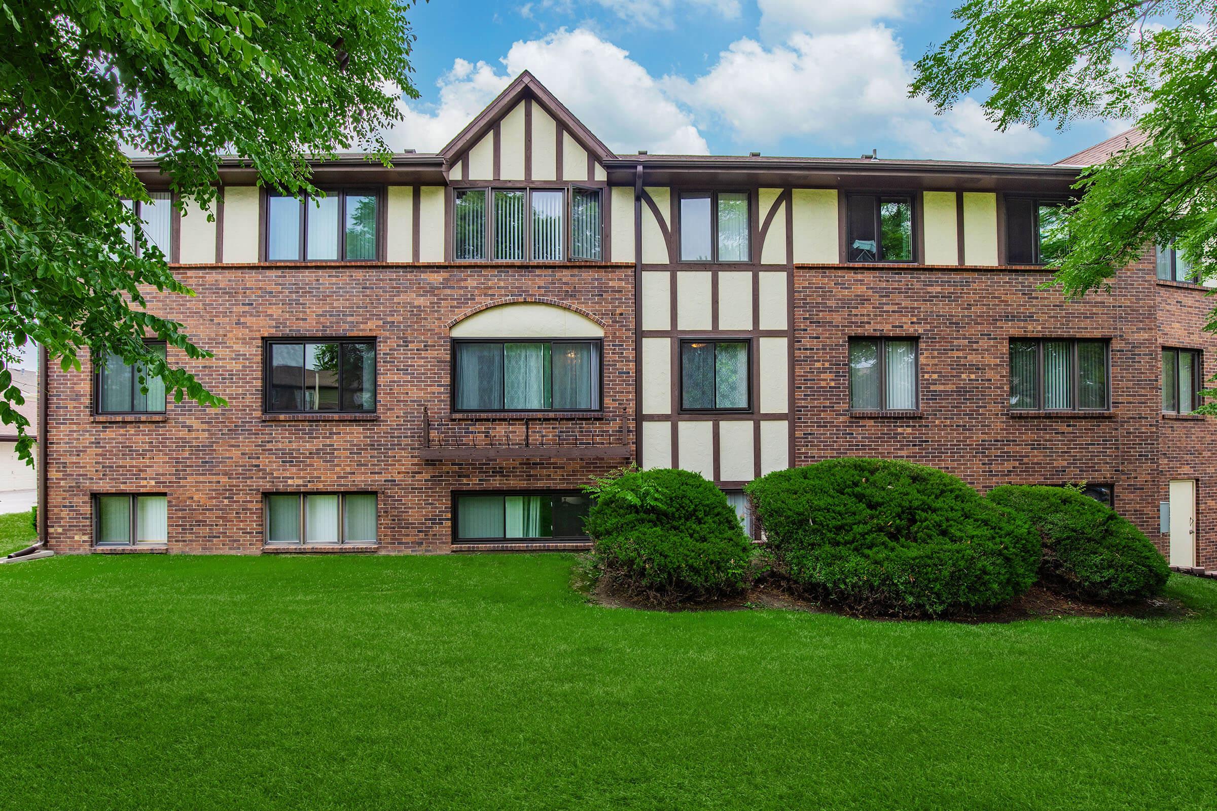 a large brick building with green grass in front of a house