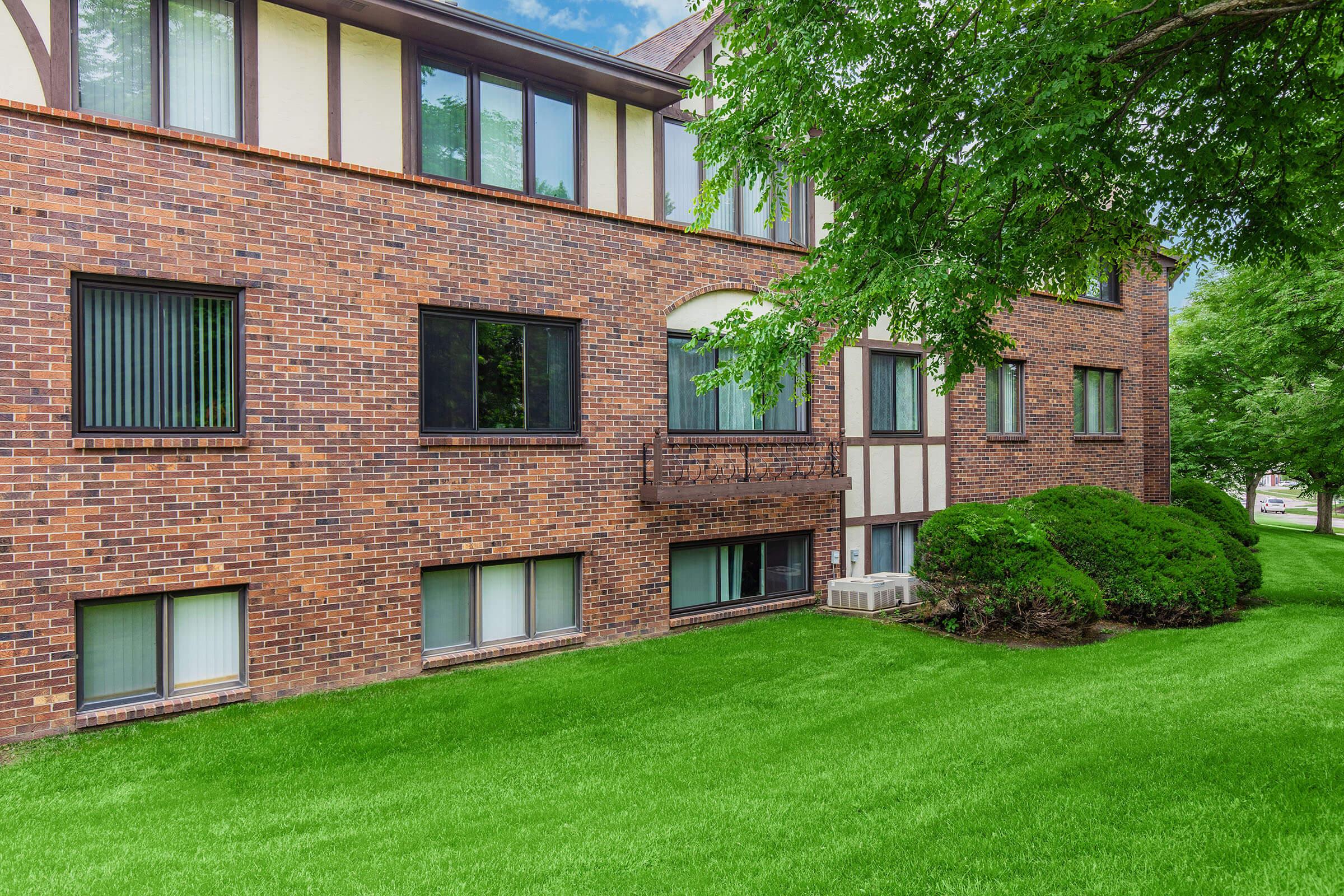 a large brick building with green grass in front of a house