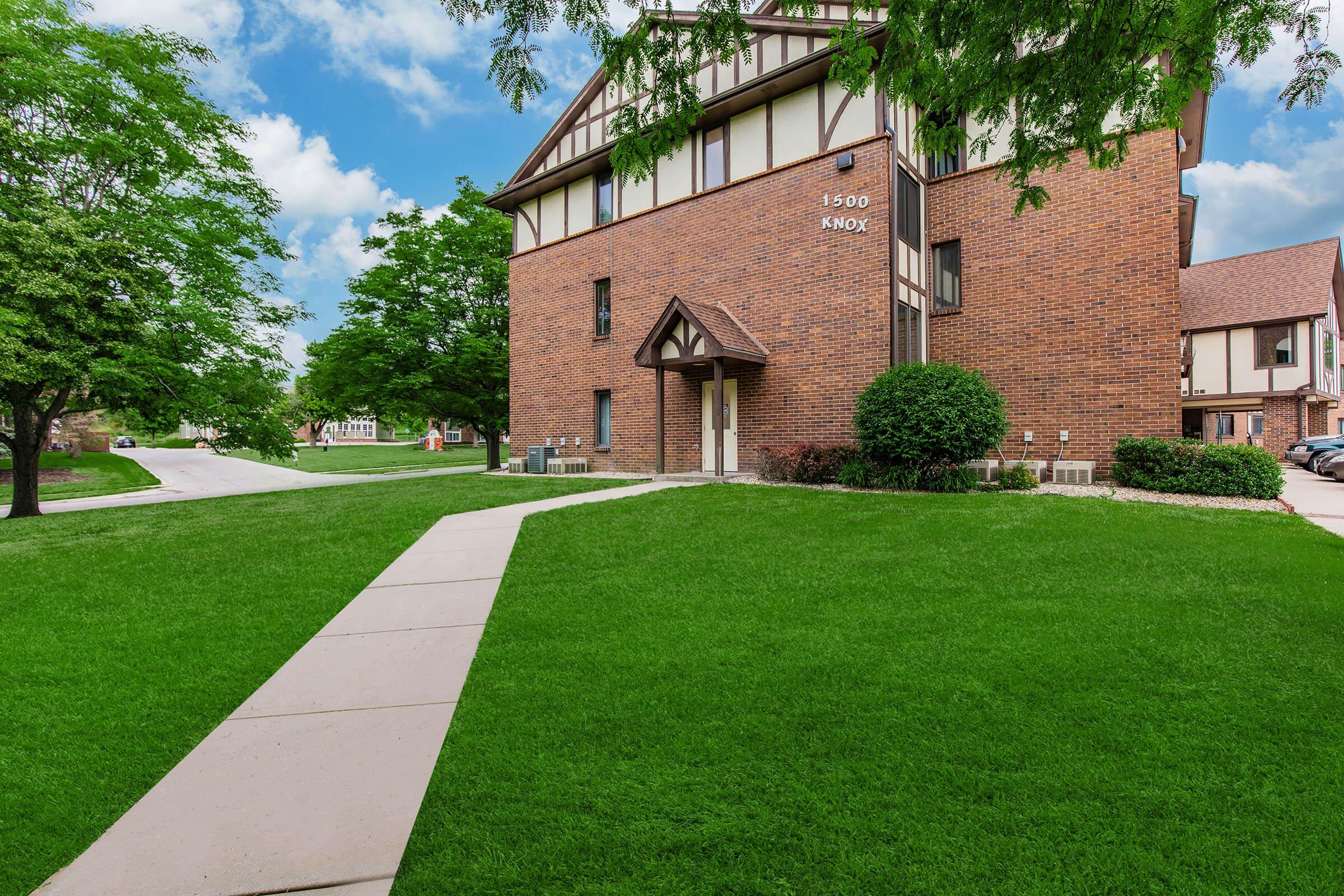 a large brick building with green grass in front of a house