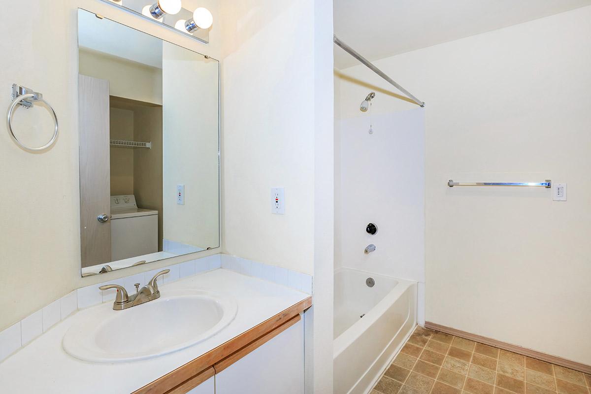 a white sink sitting under a mirror