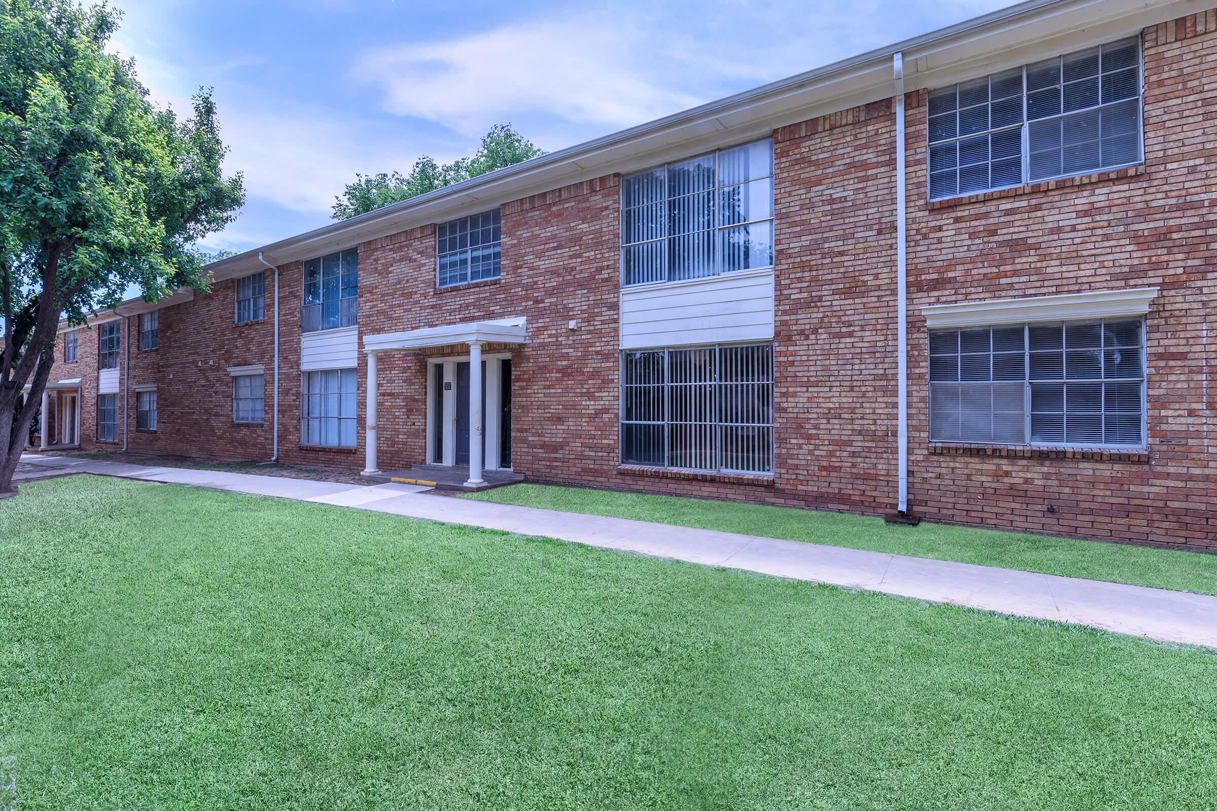 a large lawn in front of a brick building