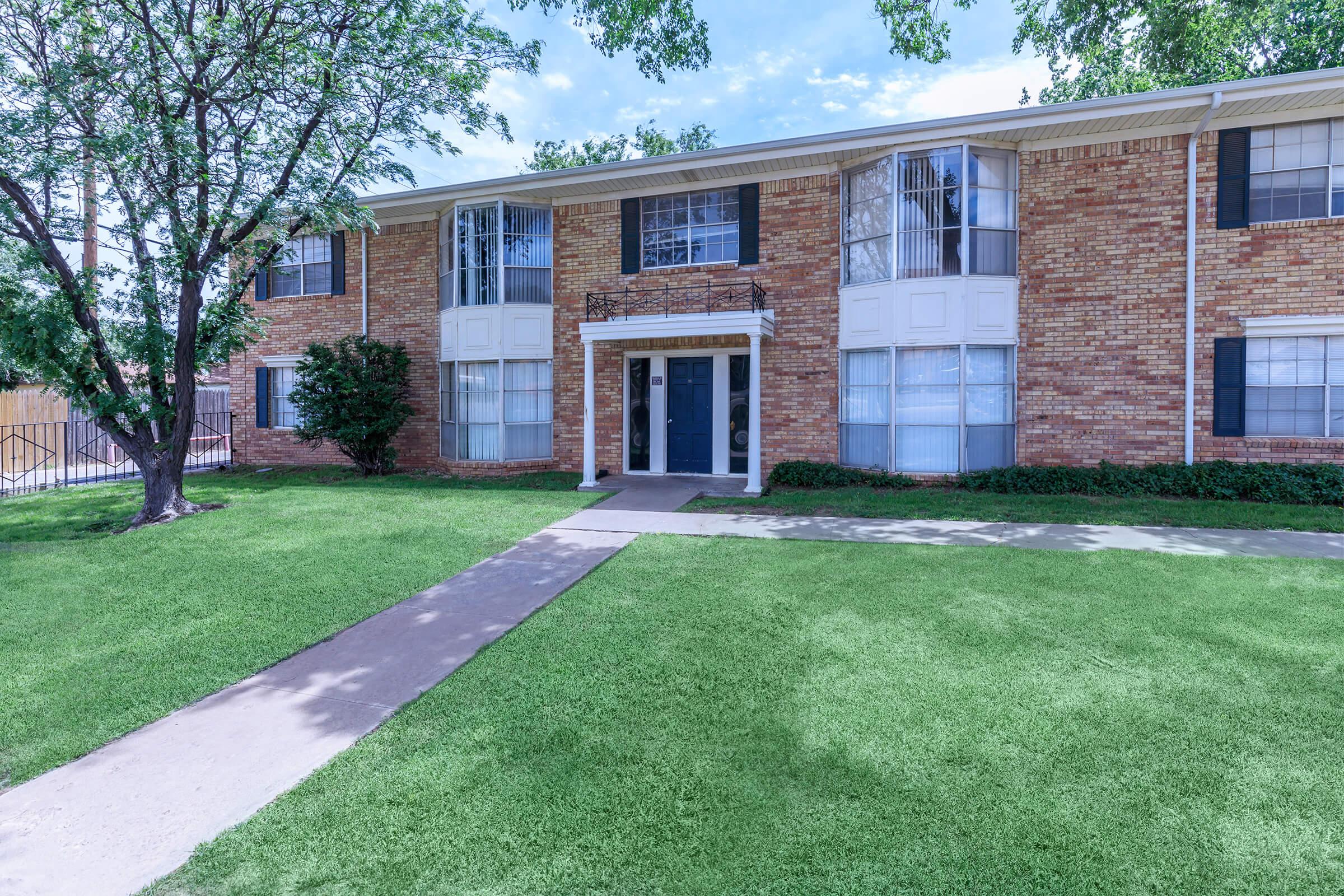 a house with a lawn in front of a brick building