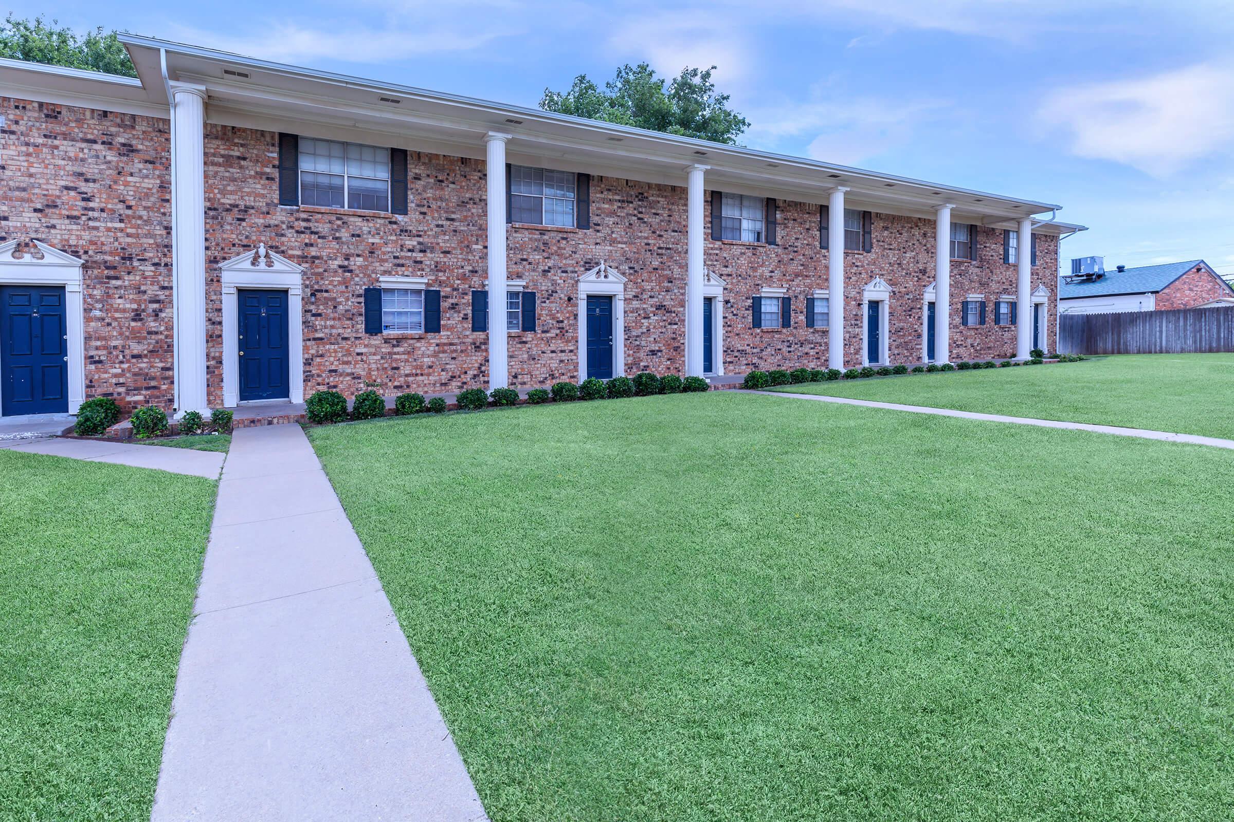 a large lawn in front of a brick building