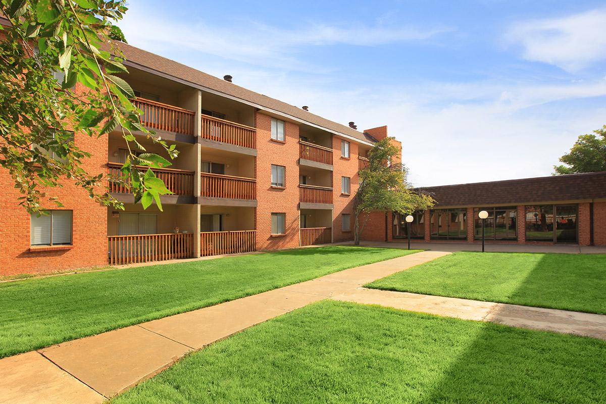 a large brick building with grass in front of a house