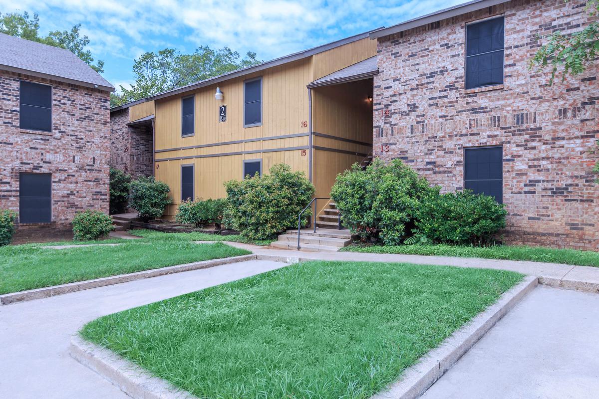 a large brick building with grass in front of a house