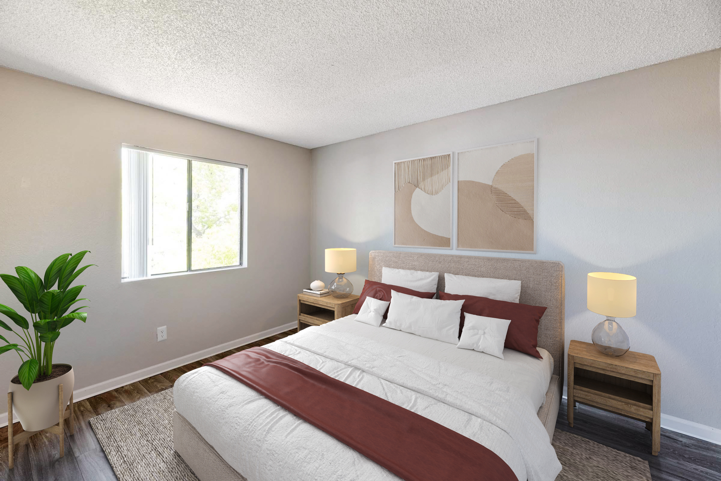 A cozy bedroom featuring a bed with a white comforter and burgundy accent pillows, two bedside tables with lamps, and a potted plant. The room has neutral walls and a window that allows natural light to brighten the space. Two abstract art pieces are hung above the headboard.