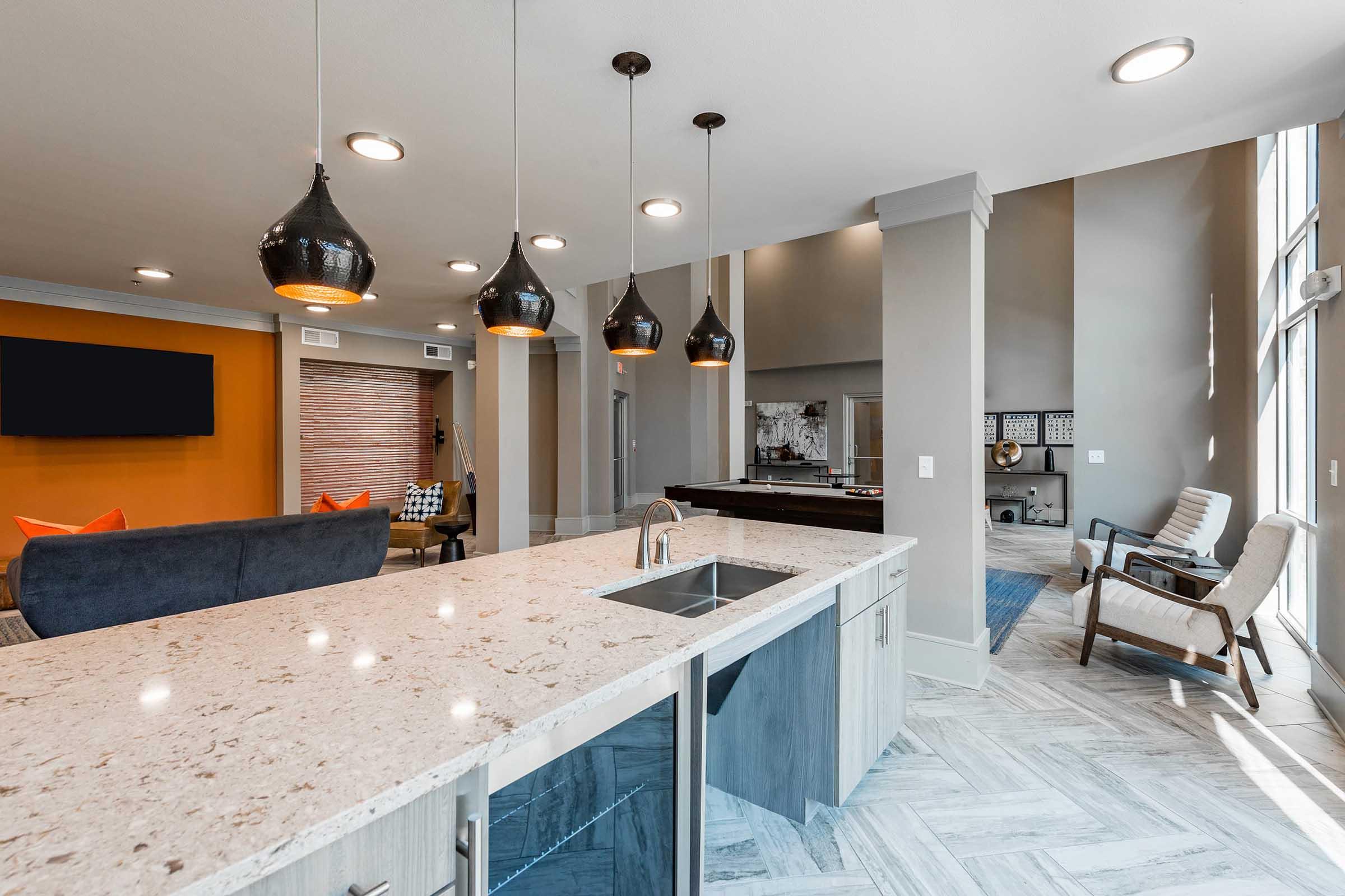 Modern kitchen with a large island featuring a sink, surrounded by stylish pendant lighting.