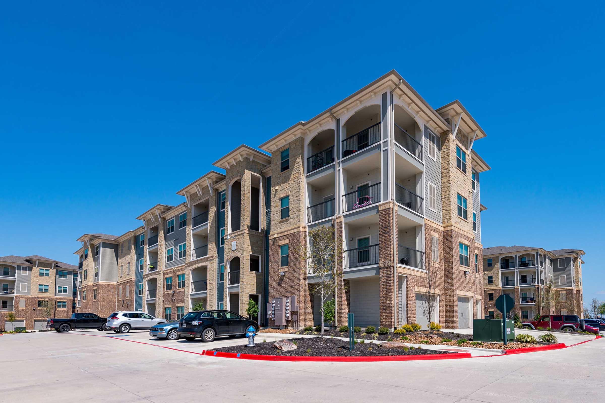 A modern multi-story apartment building featuring a mix of brick and siding exteriors.