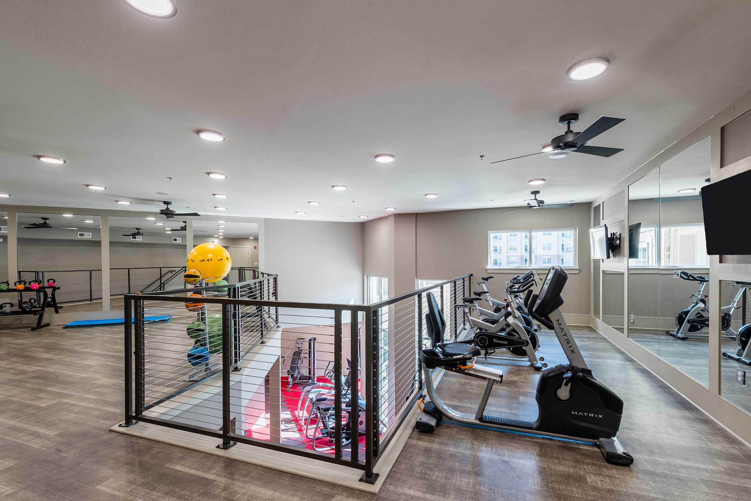 A spacious fitness center featuring exercise equipment, including stationary bikes and weights.