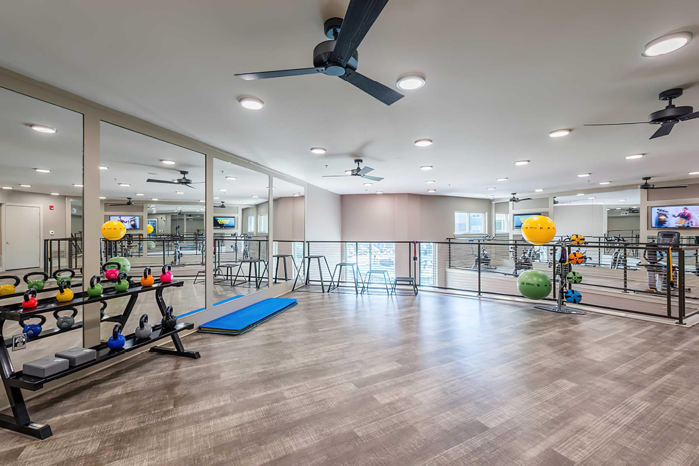 A modern gym interior featuring various fitness equipment, including weights and a workout mat.