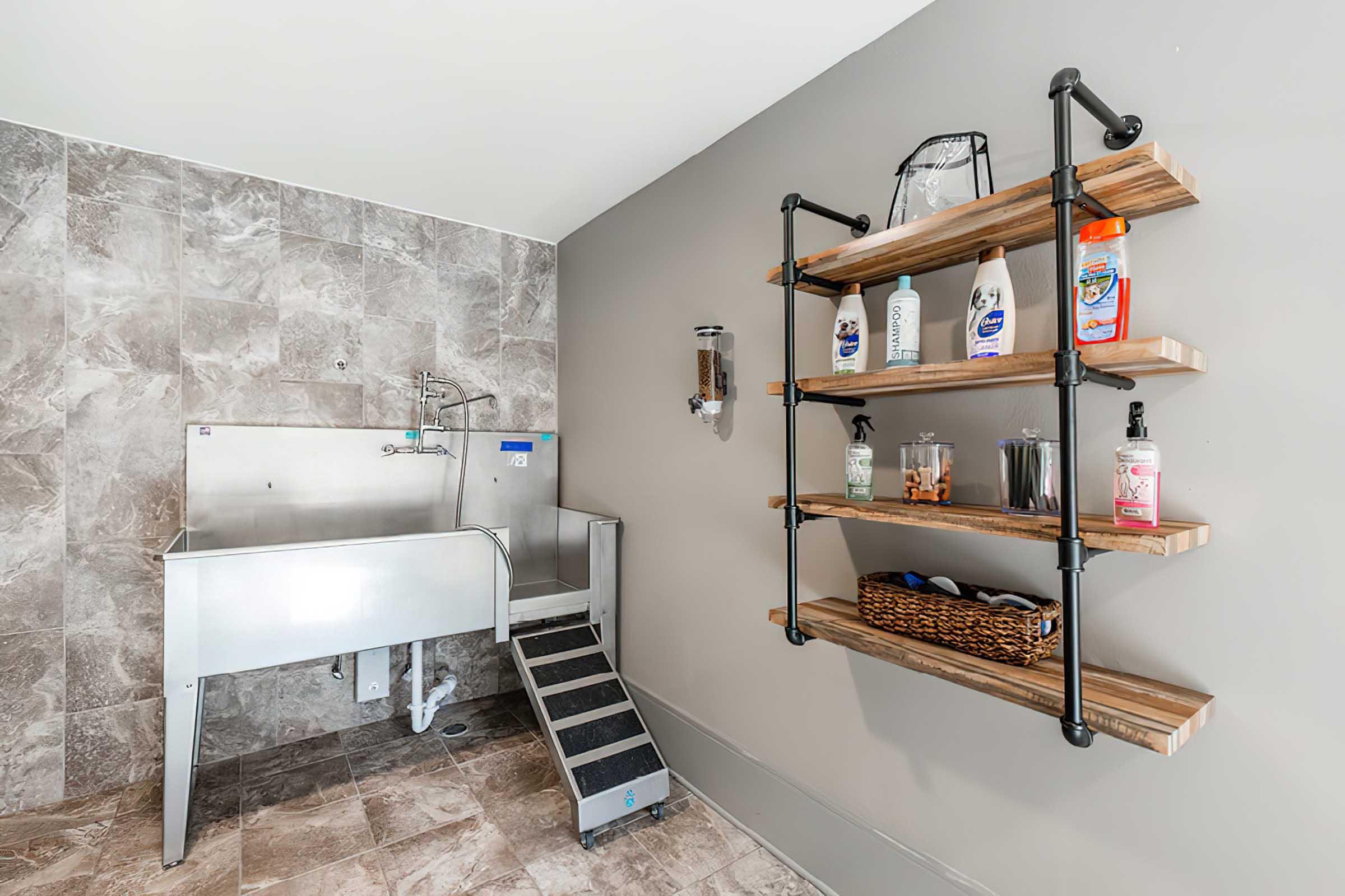 A spacious dog wash area featuring a stainless steel utility sink with a step for easy access.