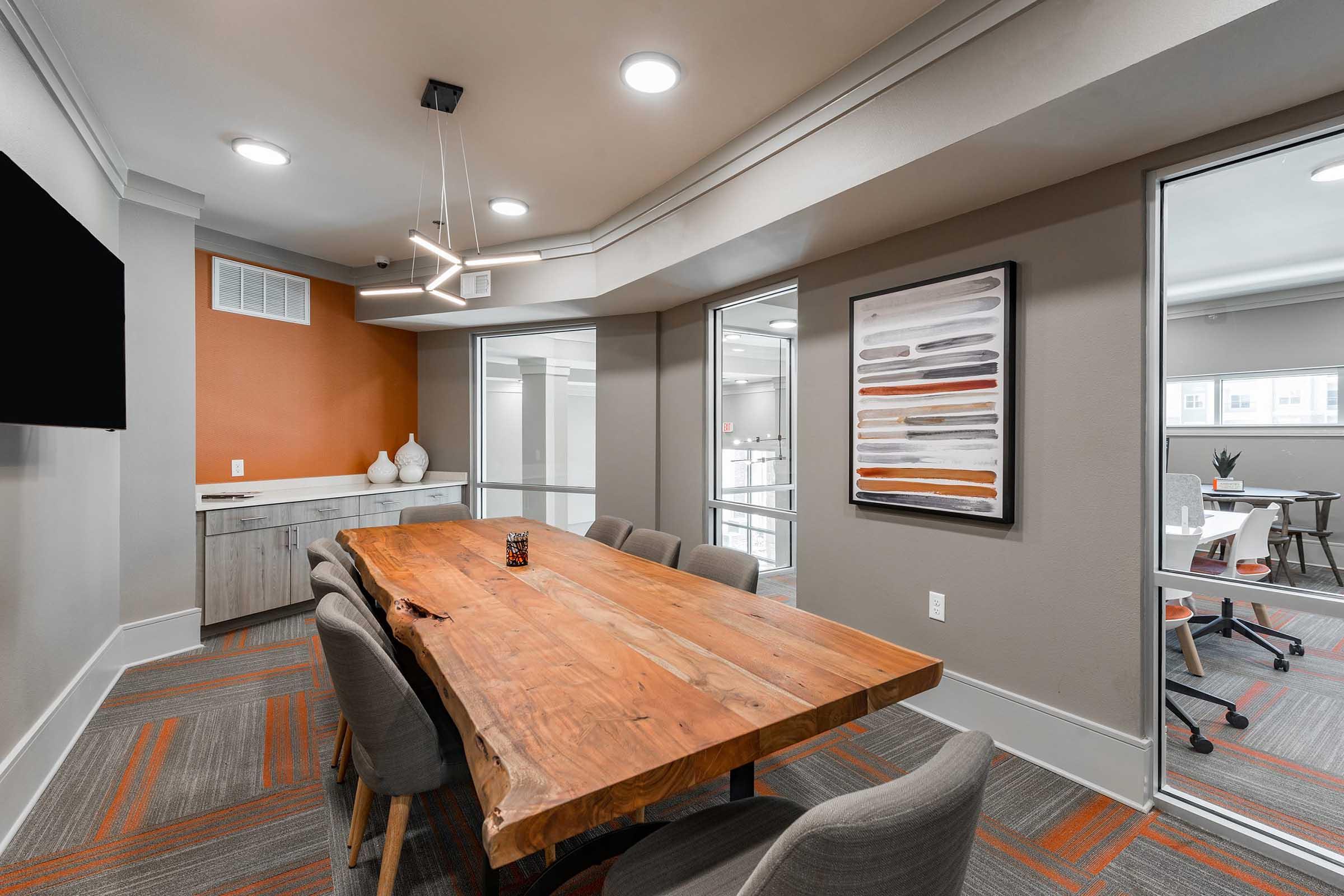 Modern conference room featuring a large wooden table surrounded by gray upholstered chairs.