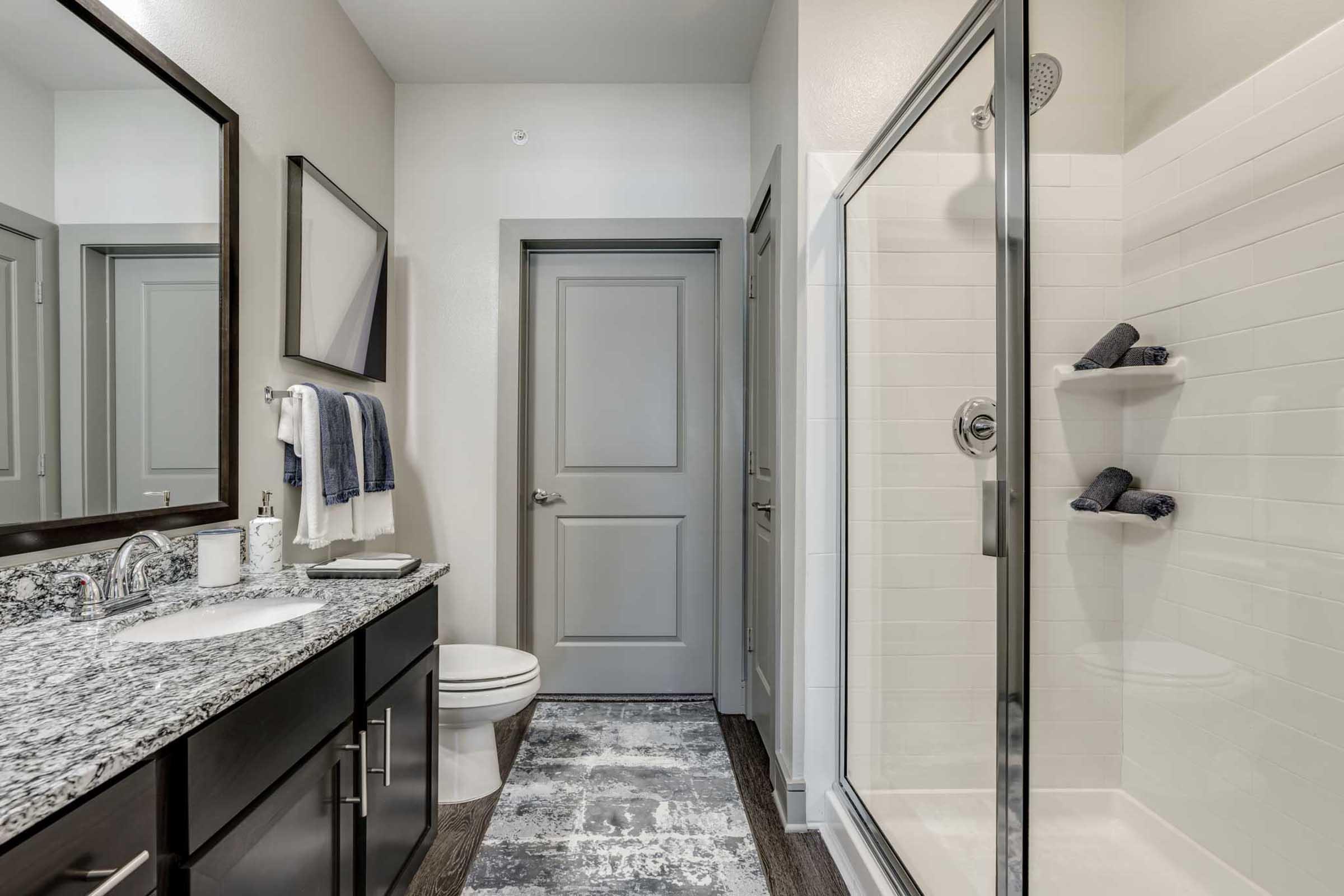 Modern bathroom featuring a sleek design with a granite countertop, undermount sink, and large mirror.