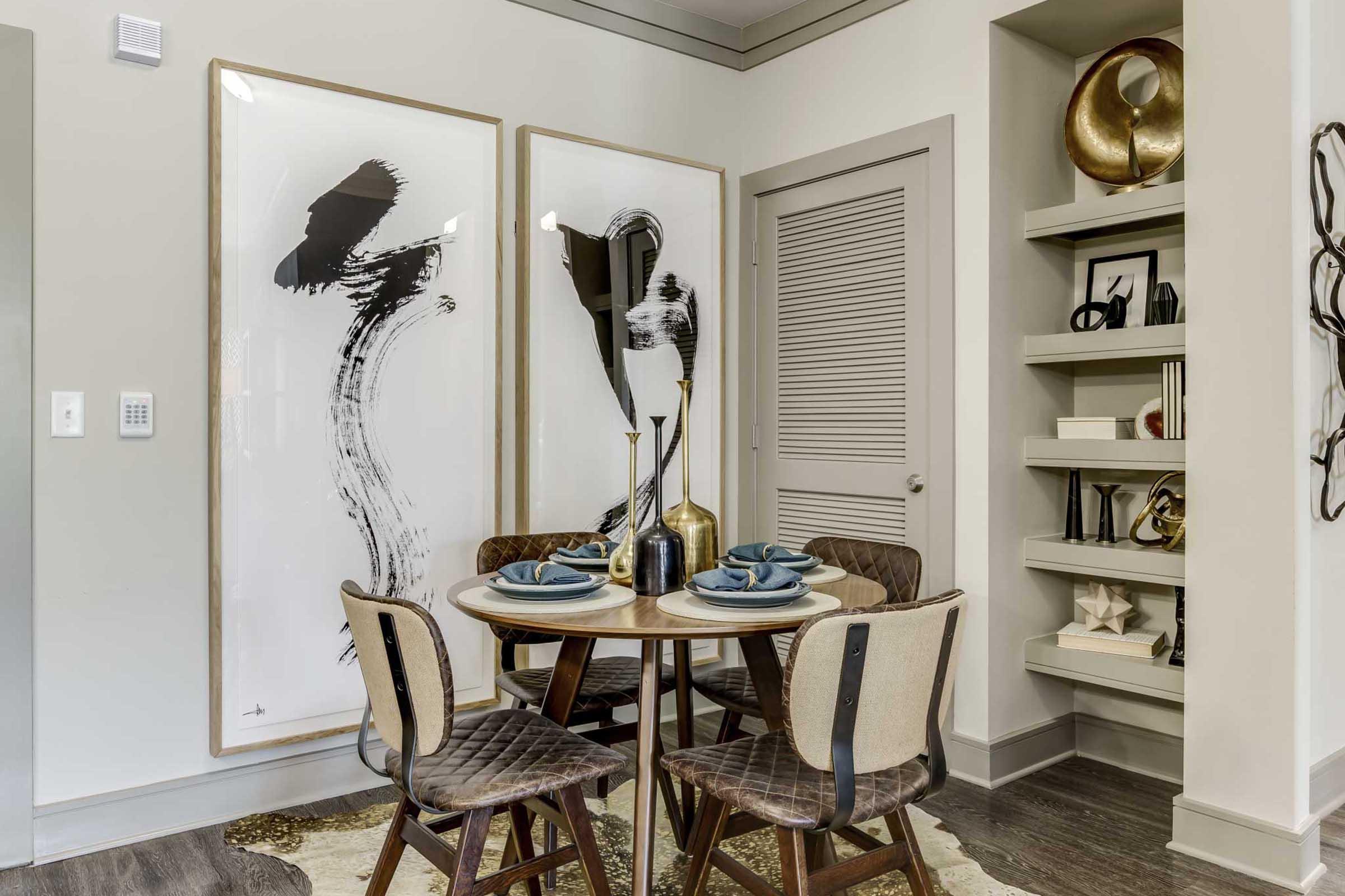 A modern dining area featuring a round wooden table set with blue plates and cutlery.