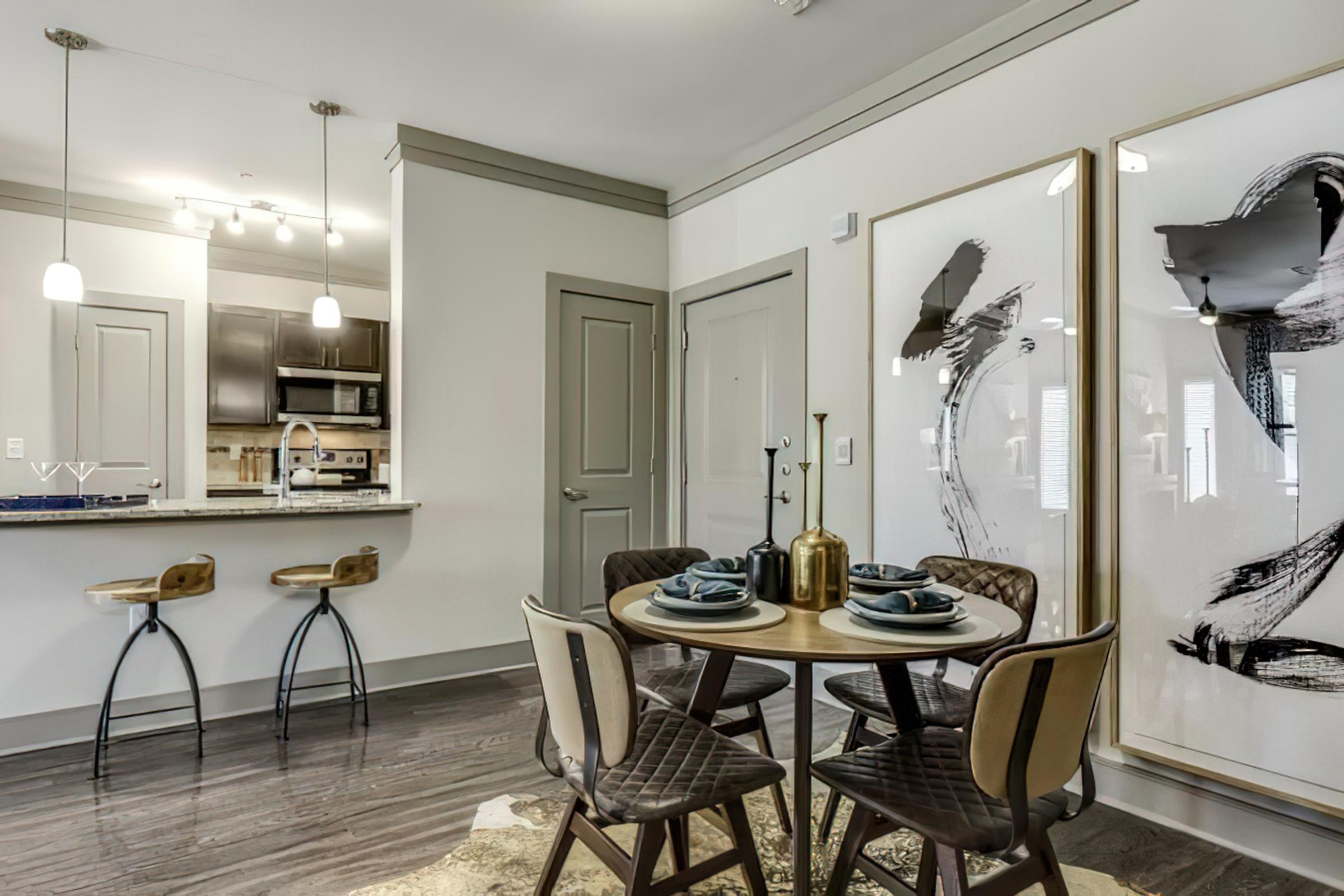 A modern dining area featuring a round wooden table set with blue plates and utensils.