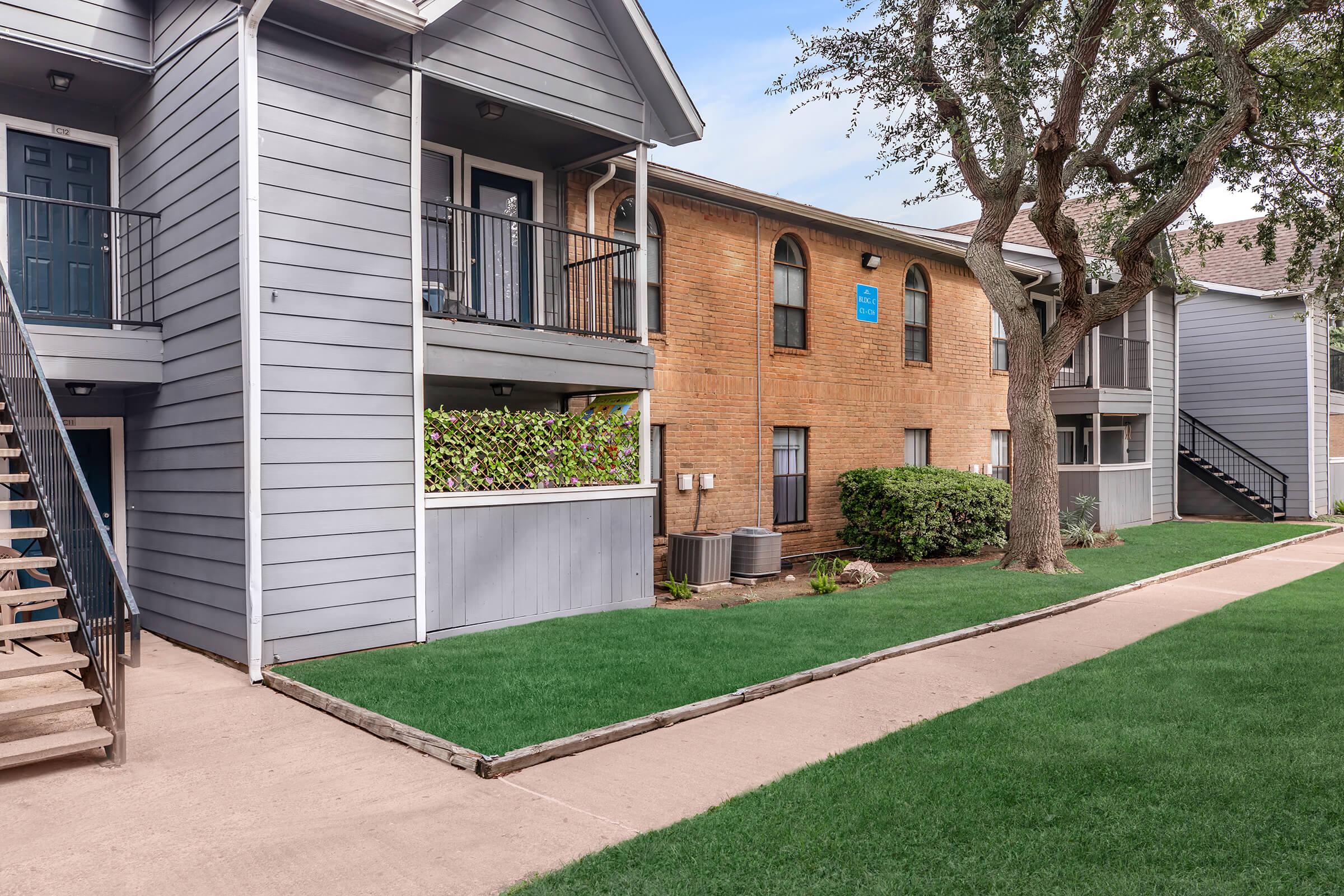 a house with a lawn in front of a brick building