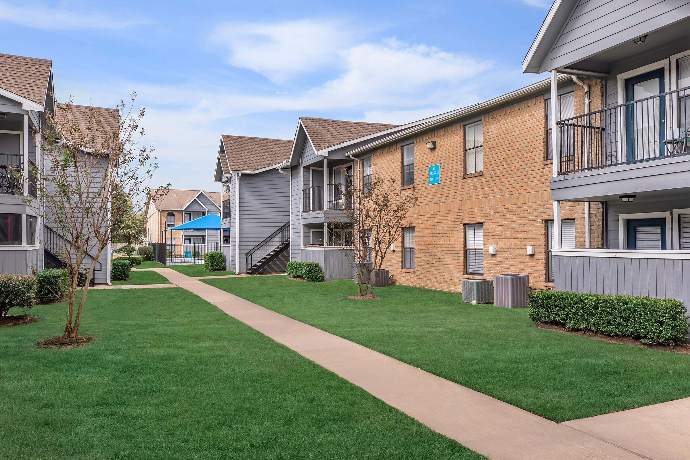 a house with a lawn in front of a brick building