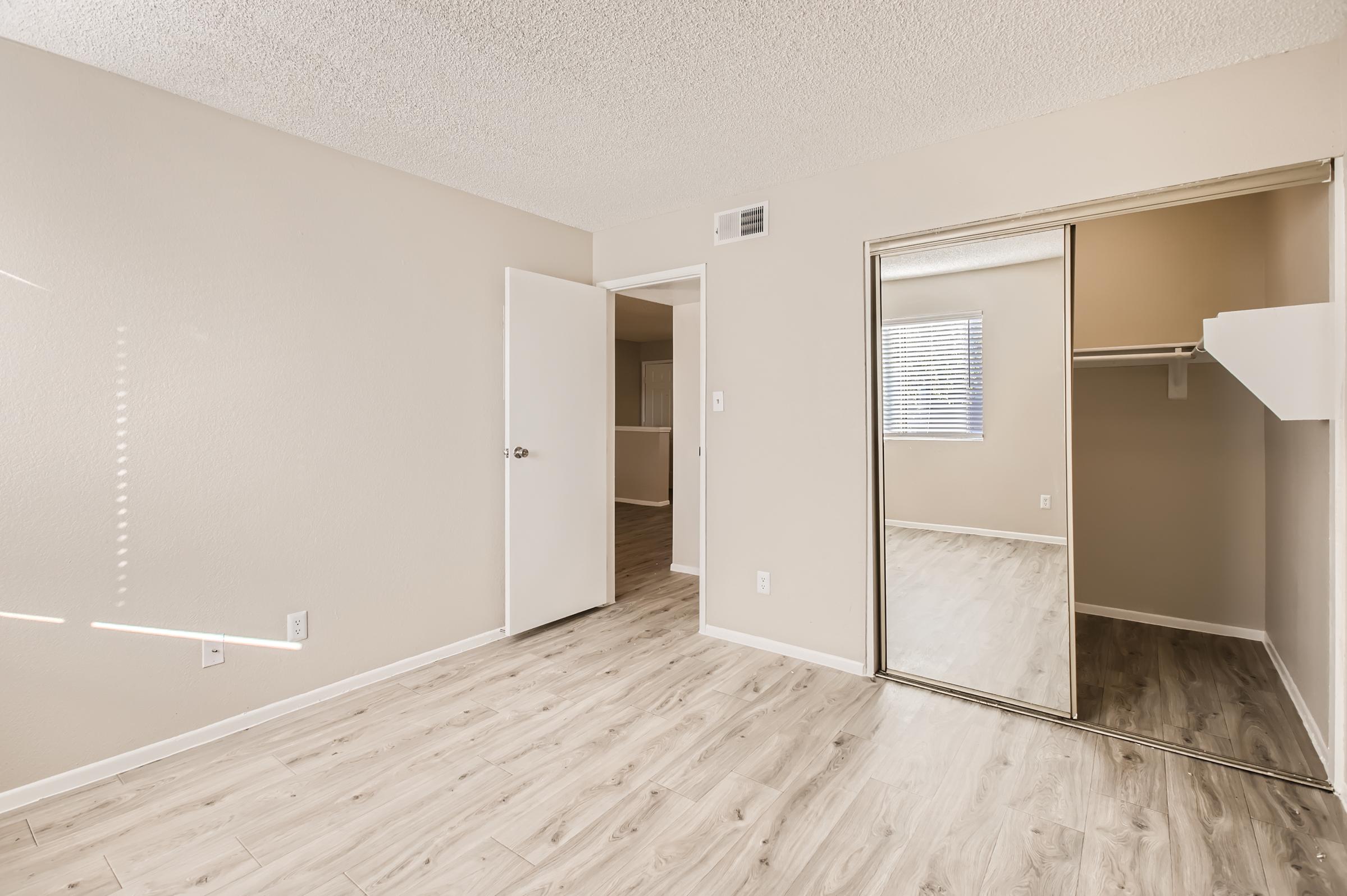 Phoenix, AZ apartment bedroom with beige walls, hardwood floors and a mirrired door to the closet