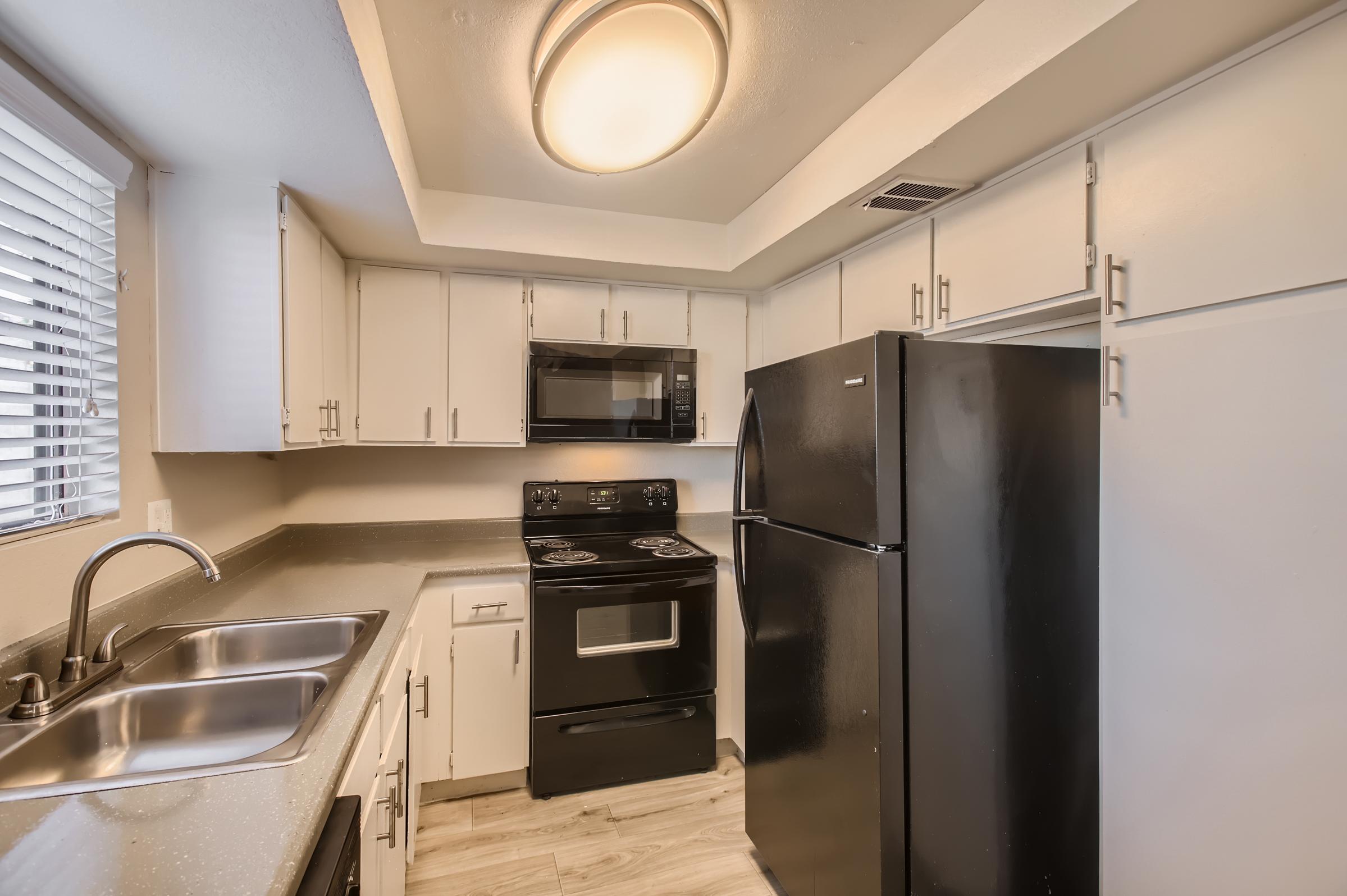 Rise Desert Cove apartment kitchen with black appliances and white cannets