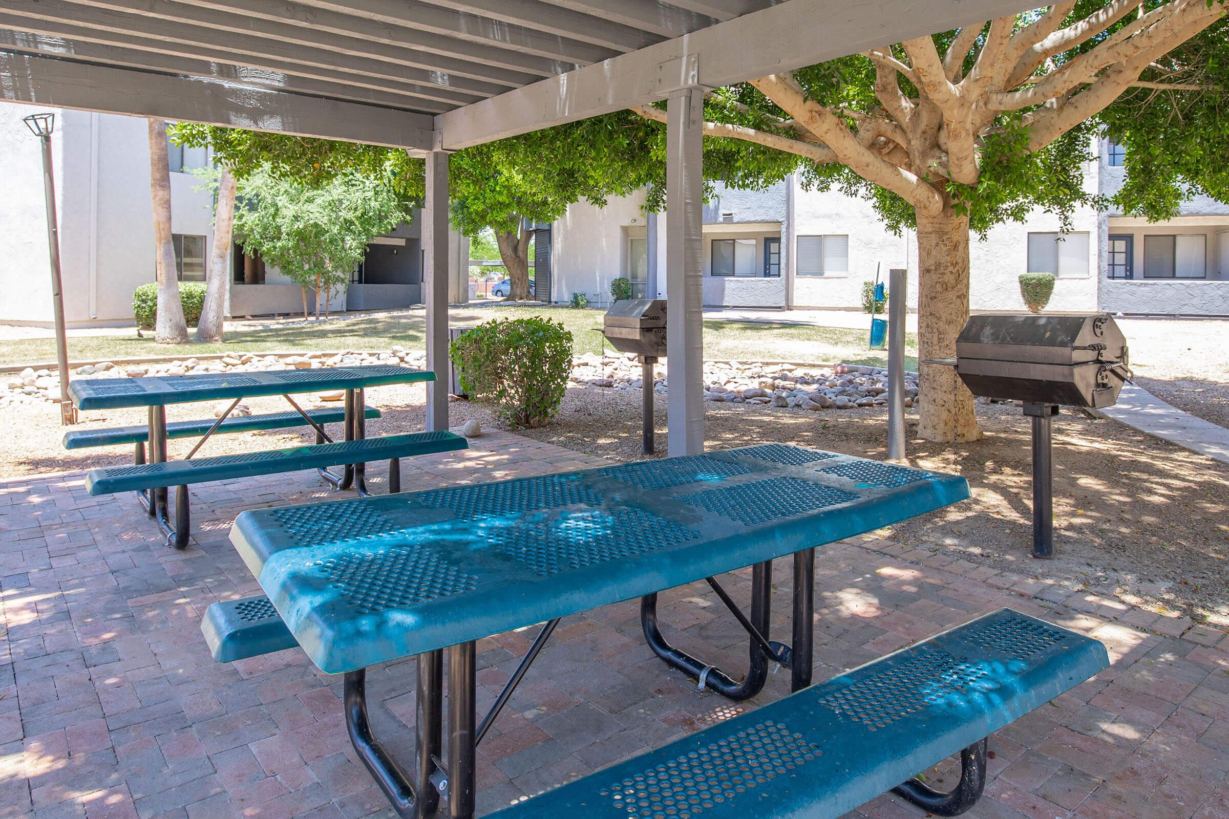 Outdoor grilling area with blue tables and benches and two gas grills at Rise Desert Cove Phoenix, Az apartments