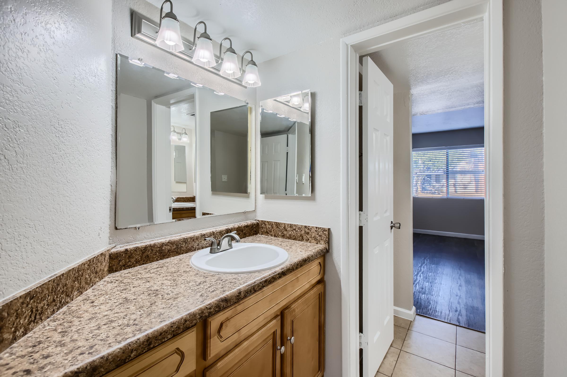 Phoenix apartment bathroom with a sink and mirror on the left and a view into the bedroom in the front
