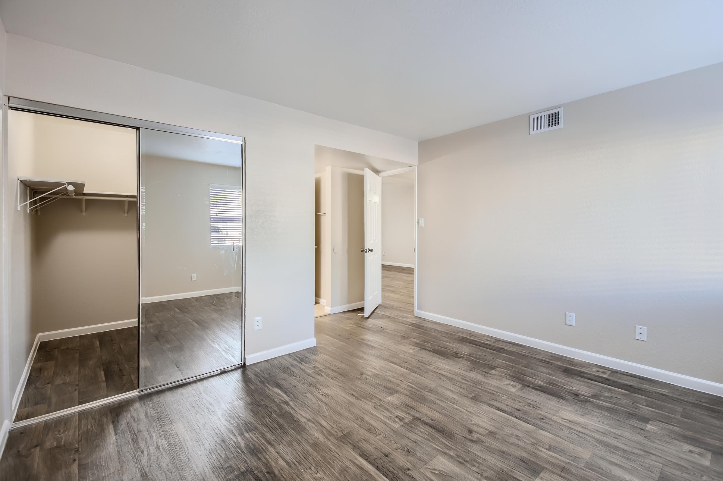 Phoenix apartment bedroom with a wooden floor, mirrored closet door and another door to the hallway