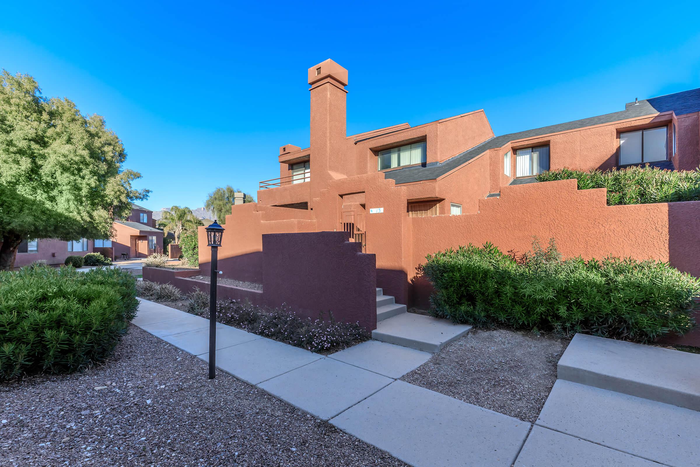 a house with bushes in front of a brick building