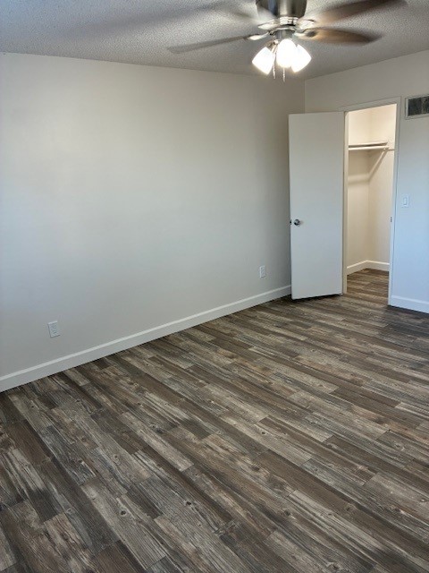 A spacious room featuring light-colored walls, a ceiling fan, and new wooden flooring. There is a closed door leading to a closet, and the overall ambiance is bright and inviting, suitable for various uses such as a bedroom or office.