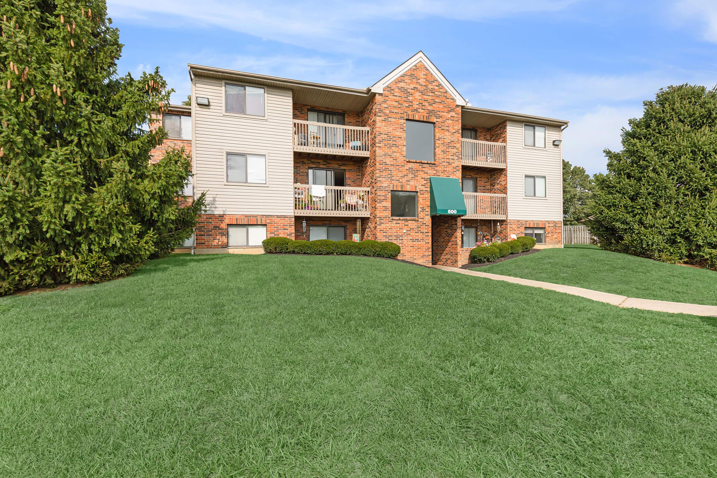 a large brick building with green grass in front of a house