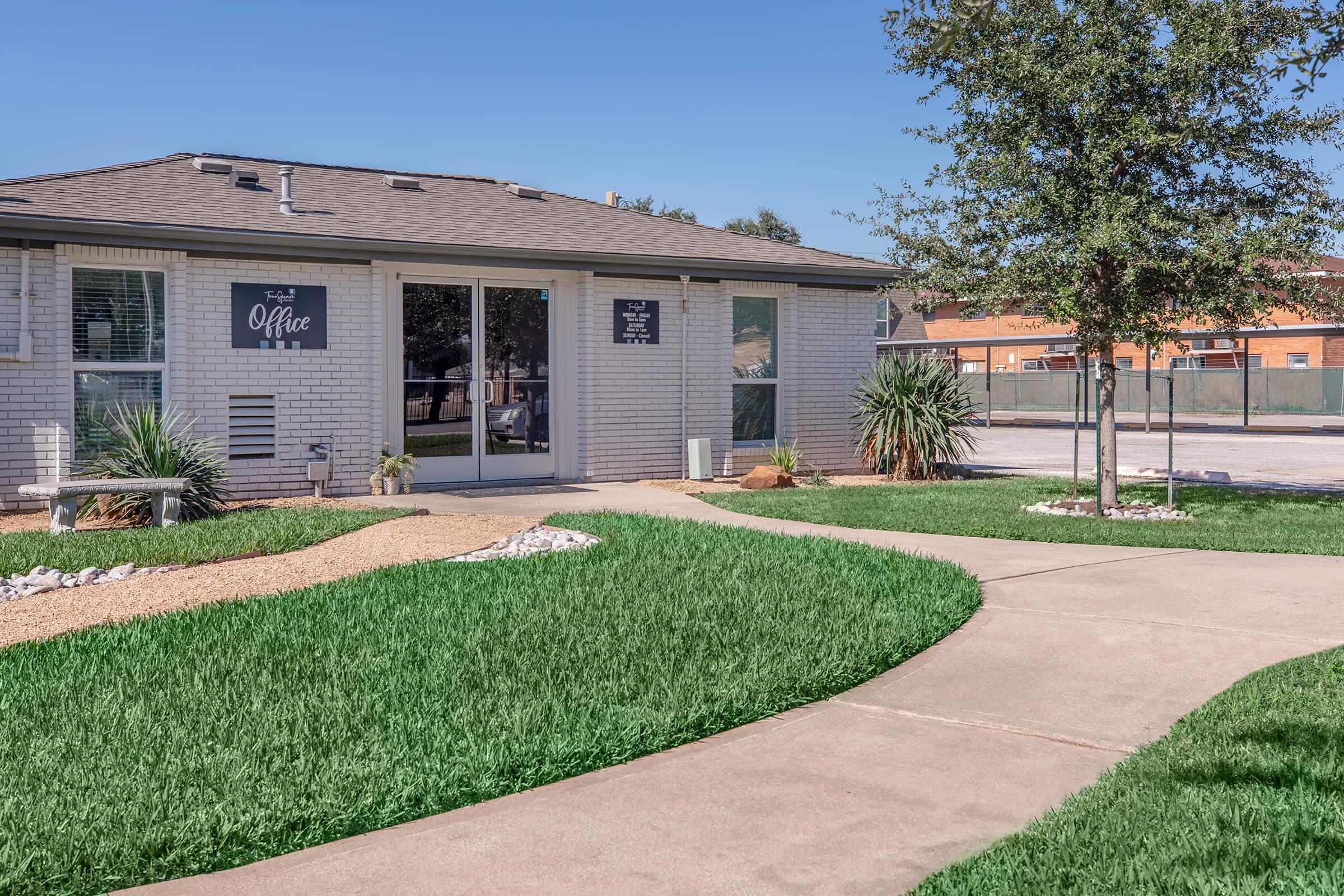 a large brick building with grass in front of a house