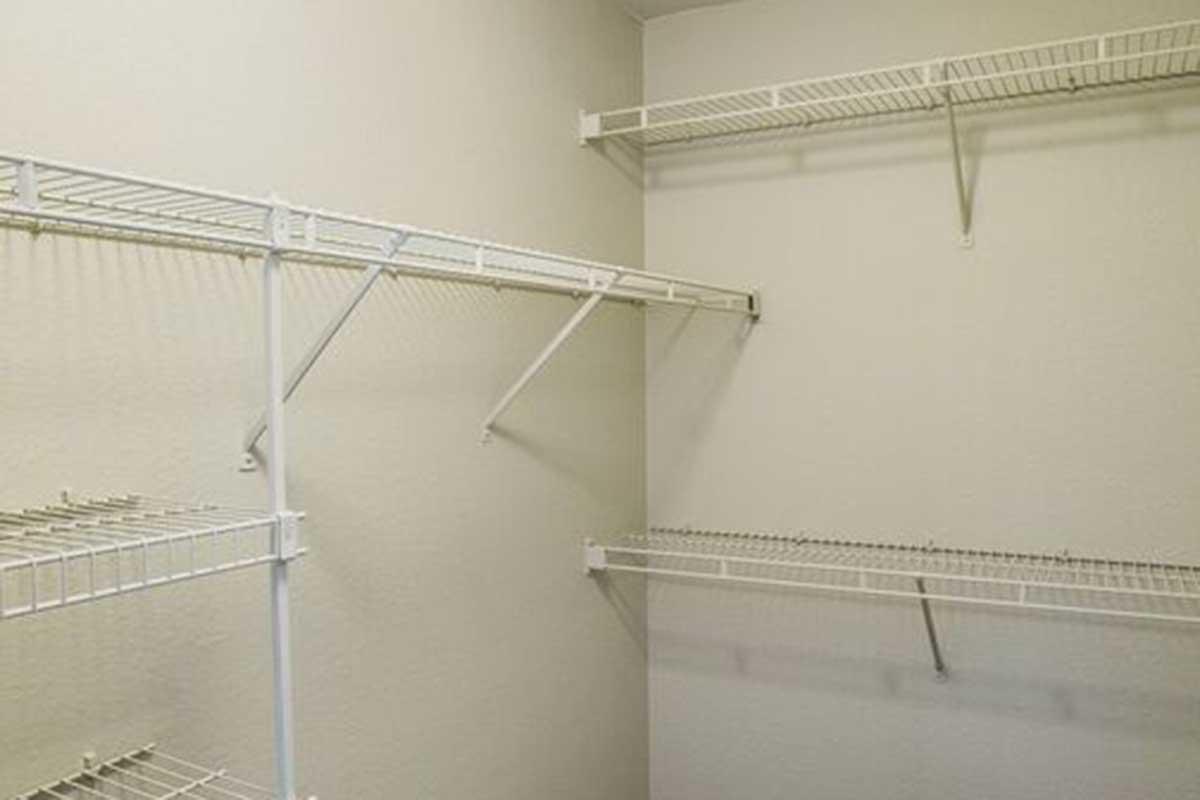 Empty closet with white wire shelving attached to light-colored walls. The shelves are arranged at various heights, providing storage space but currently devoid of any items.