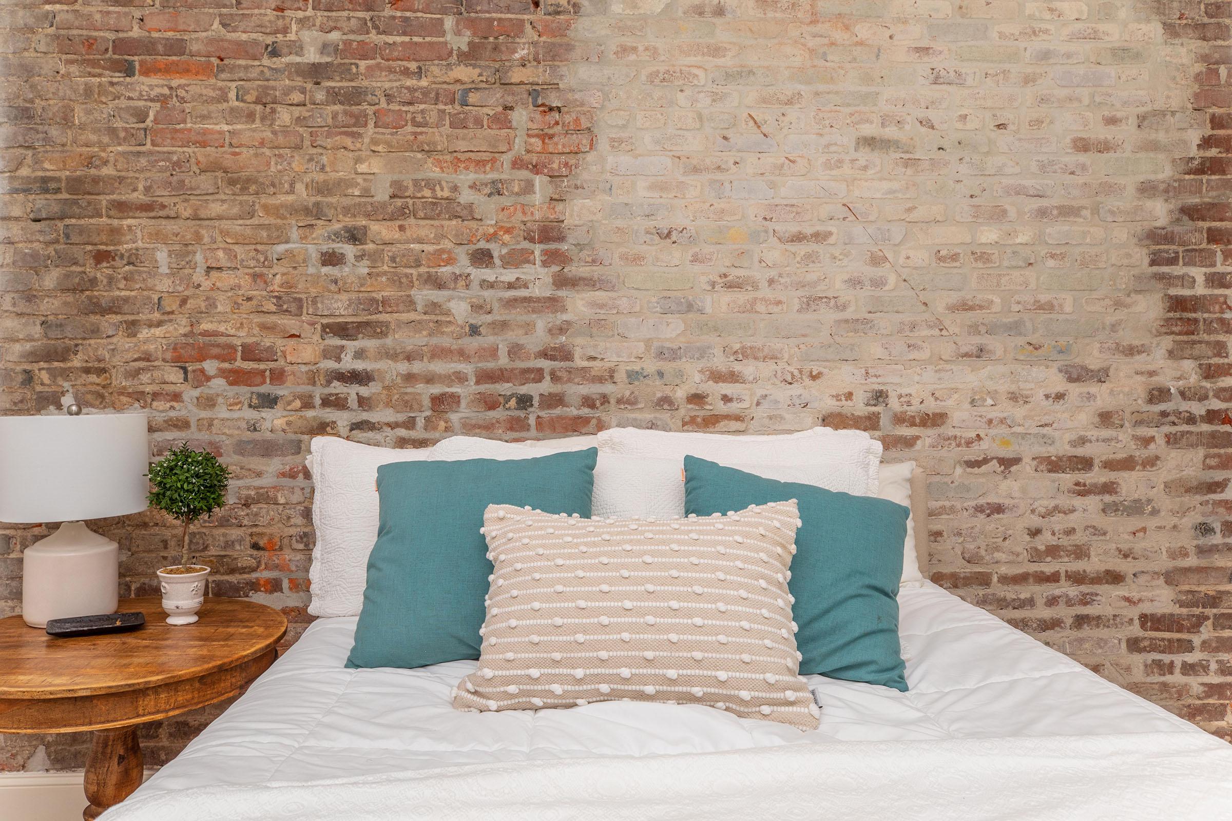 a bedroom with a brick wall
