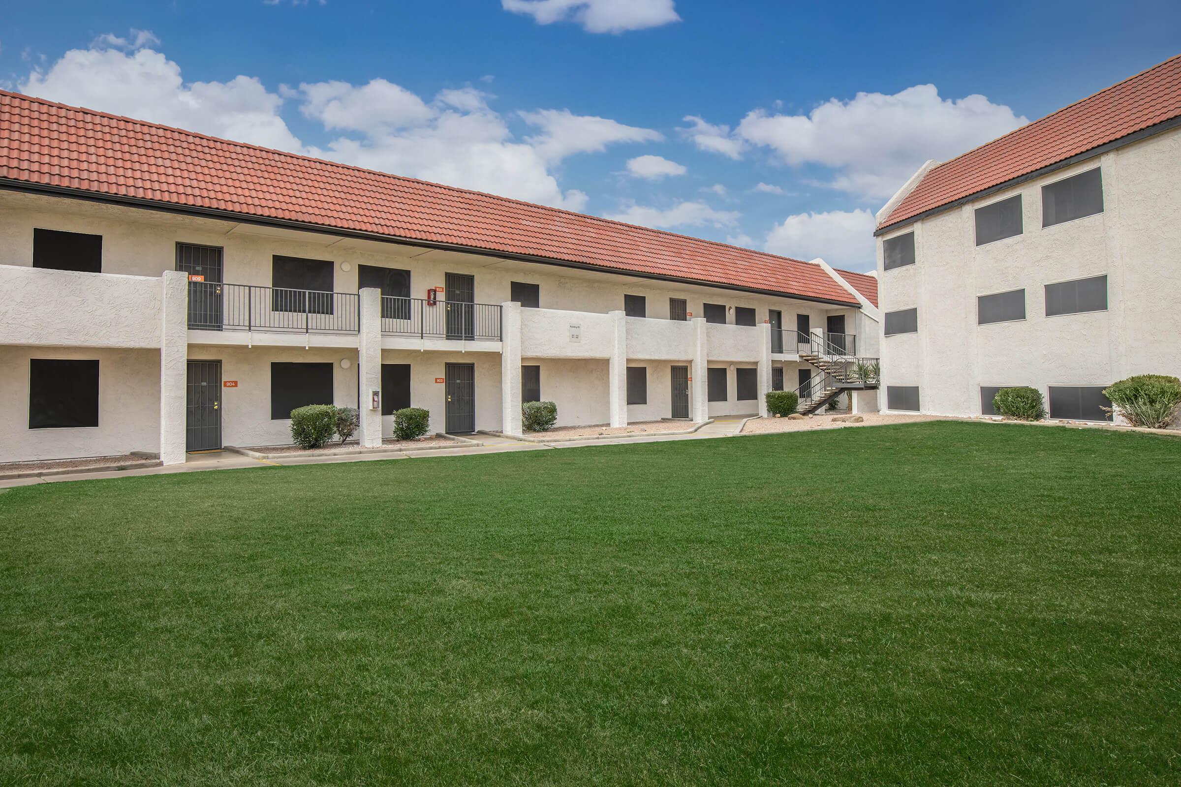 a large brick building with grass in front of a house