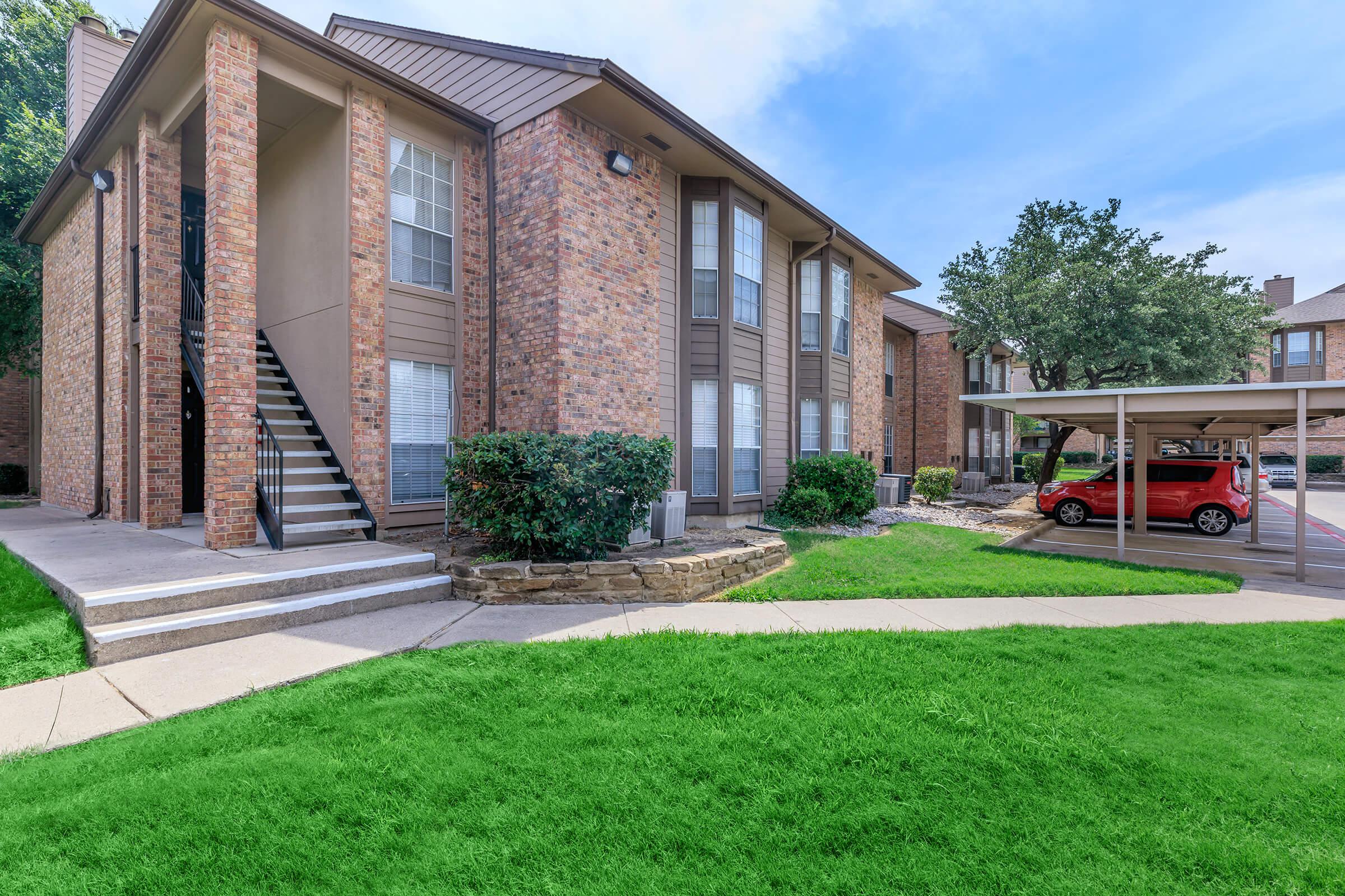 a house with a lawn in front of a brick building