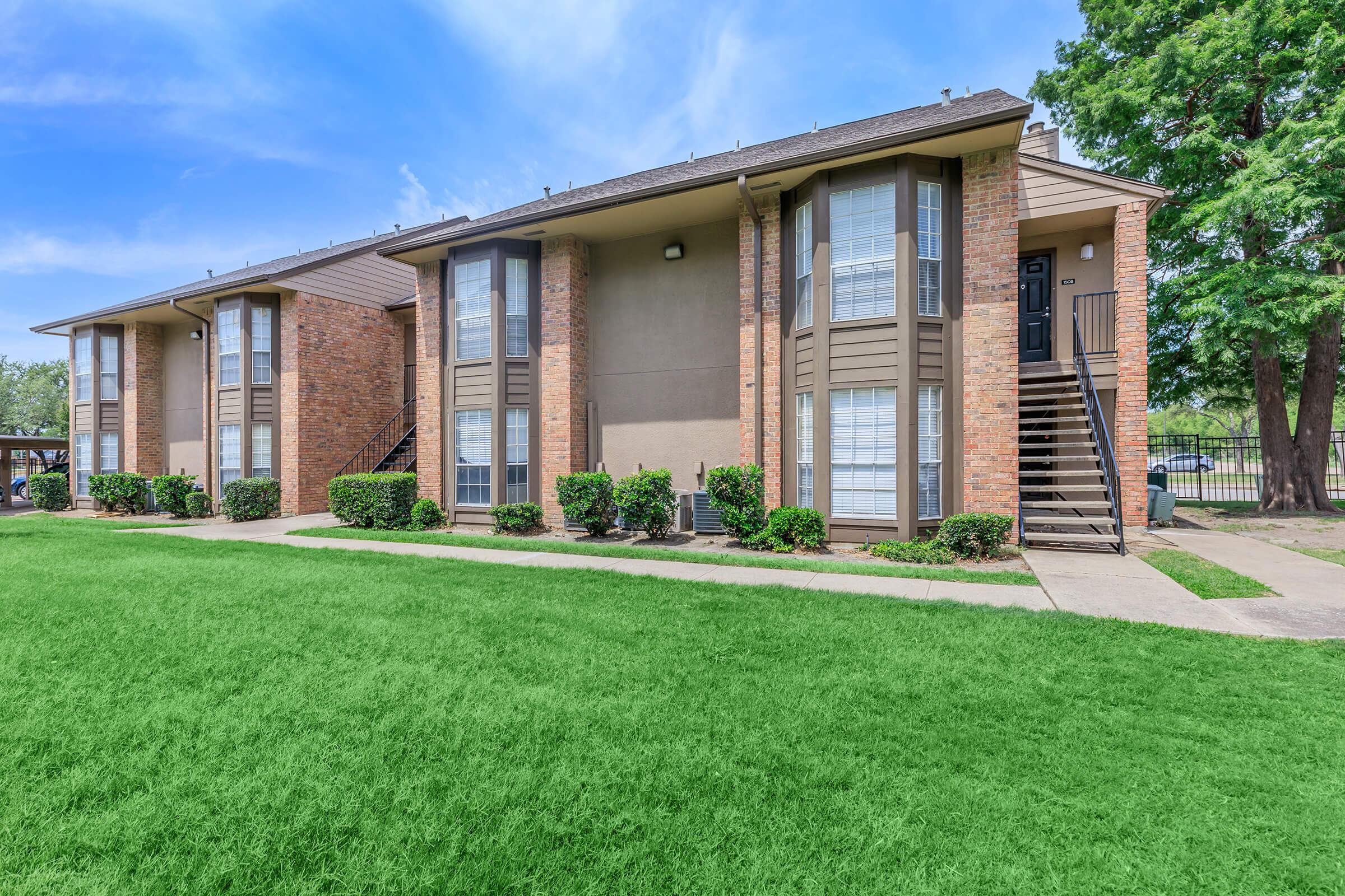 a large brick building with grass in front of a house