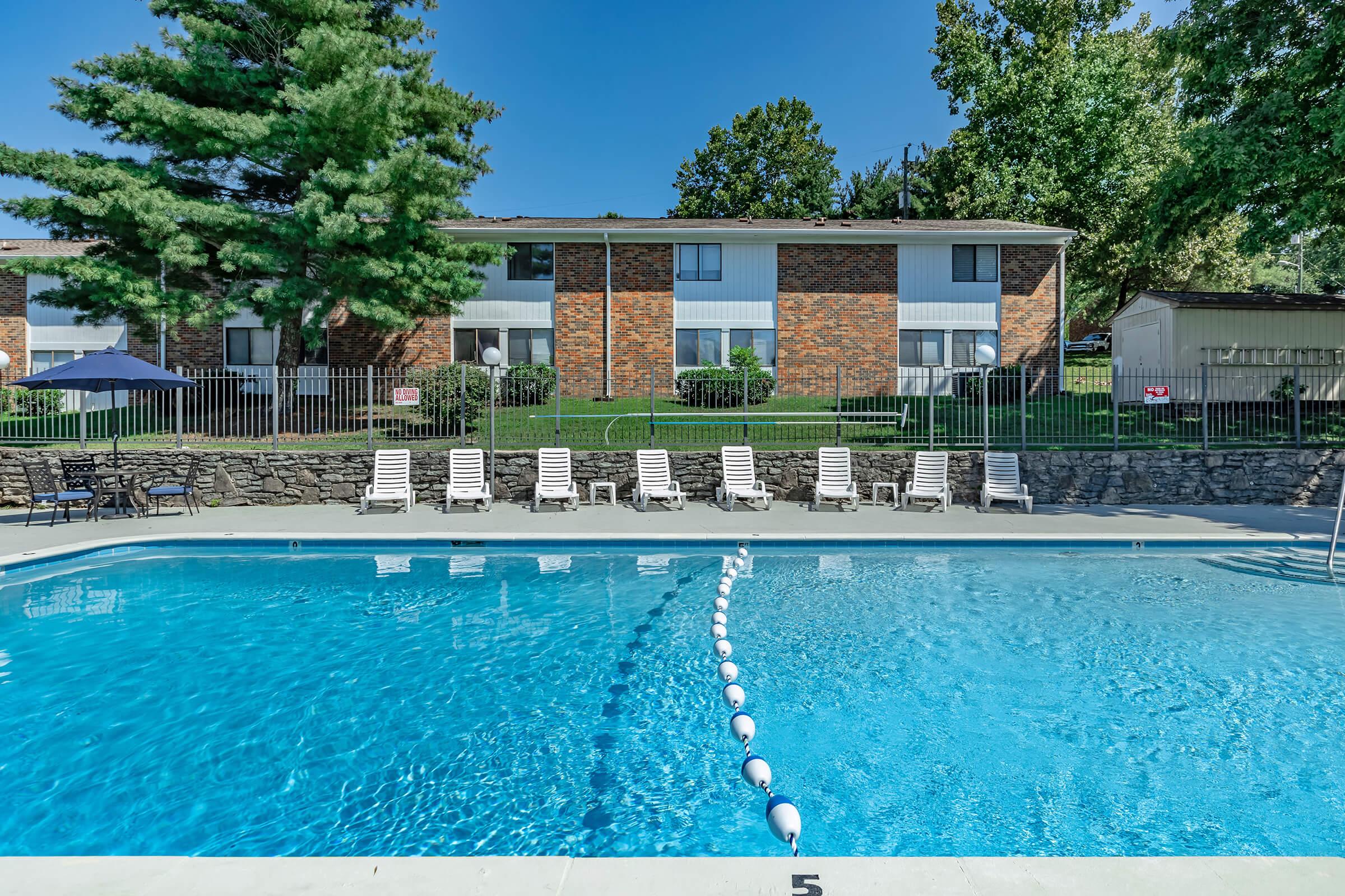 Swimming Pool with Deck Chairs and Apartment Building