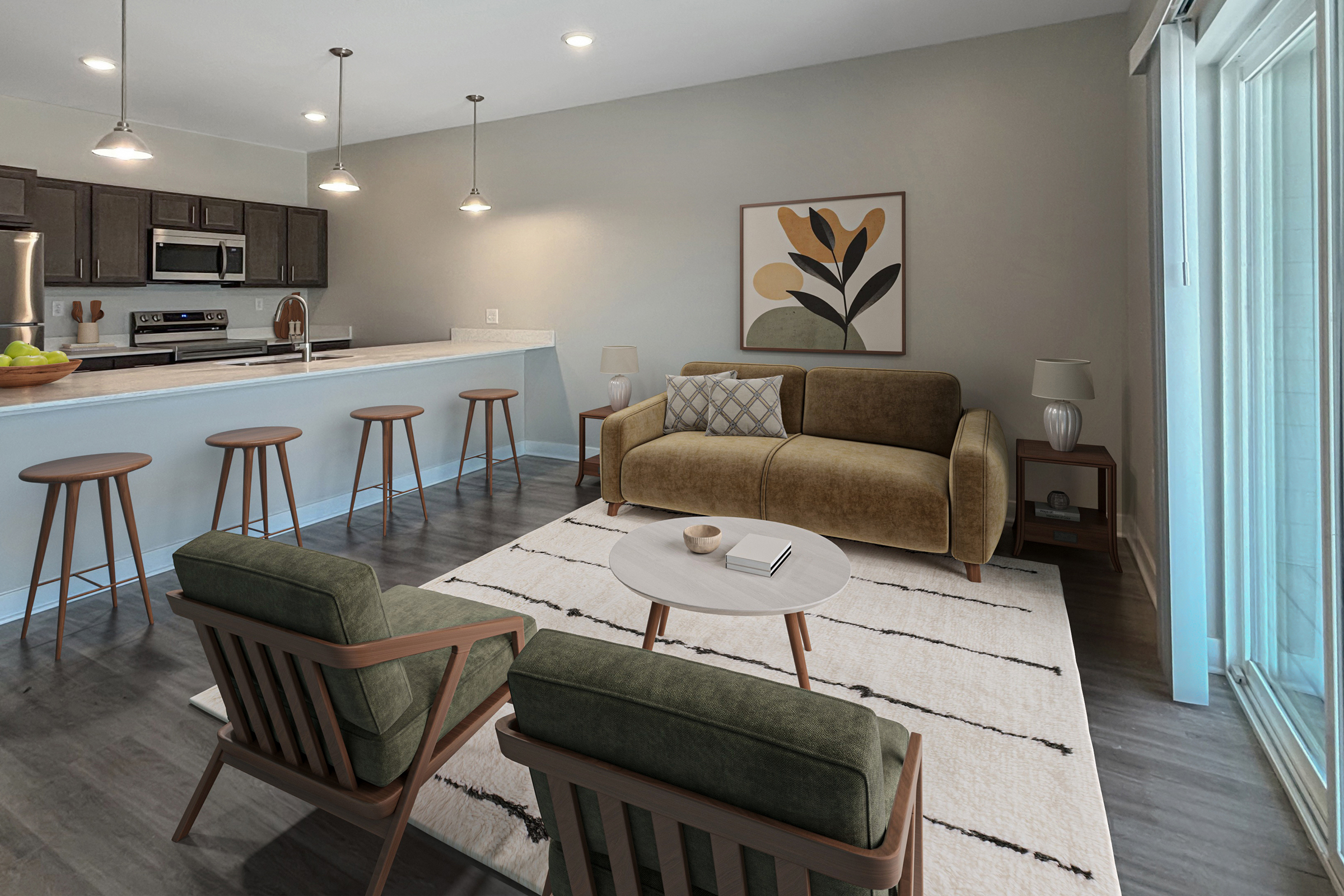 A modern living room featuring a comfortable brown sofa with patterned cushions, two green armchairs, and a round coffee table. The space includes a bar area with high stools, a kitchen in the background, and large windows letting in natural light. Decorative artwork and simple decor enhance the inviting atmosphere.