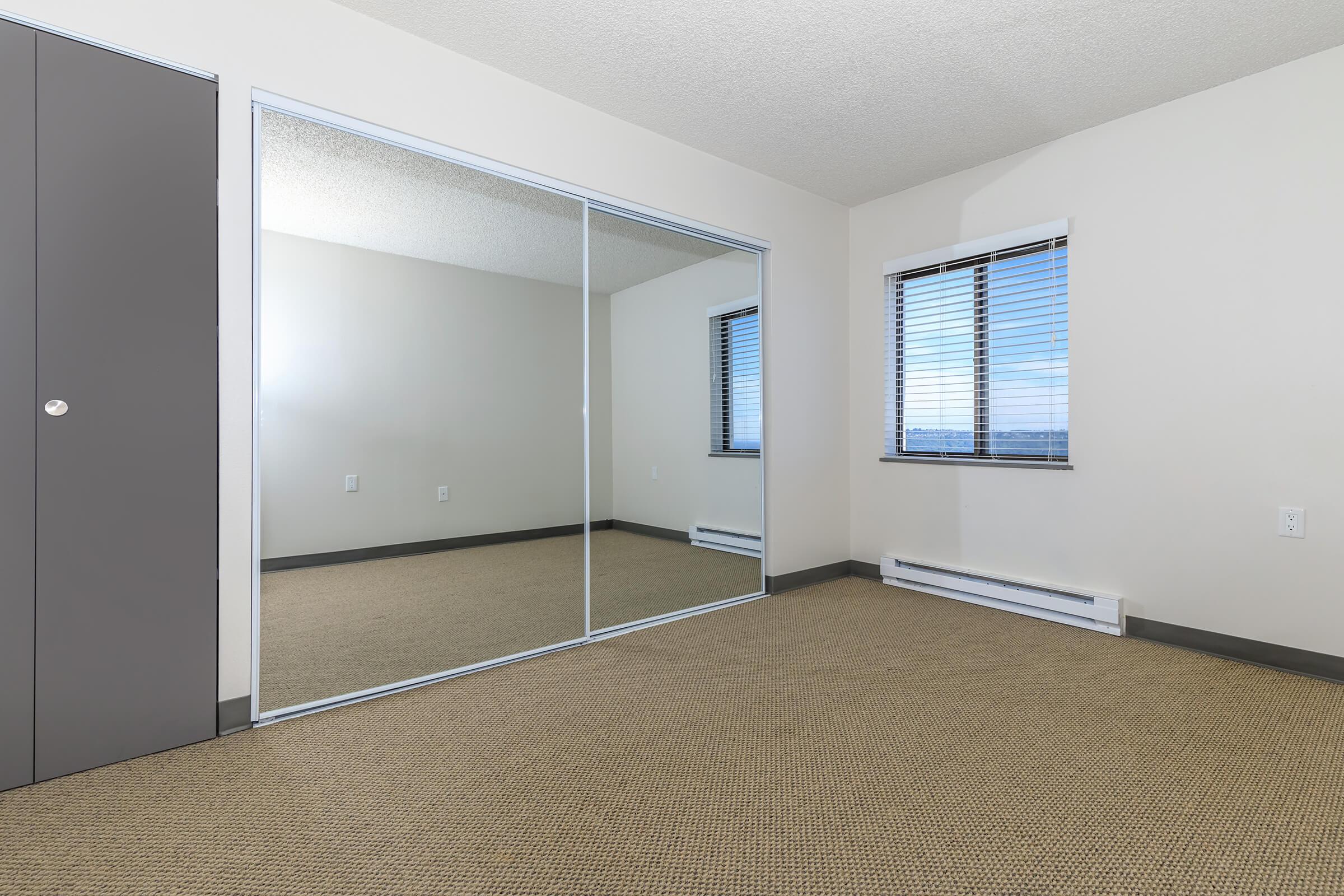 Dog-Friendly Apartments in Tacoma WA - Orion - Unfurnished Bedroom with Carpet, Mirrored Closet, and Window