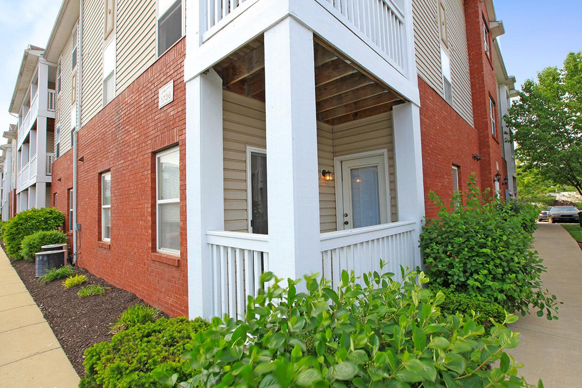 a house with bushes in front of a brick building